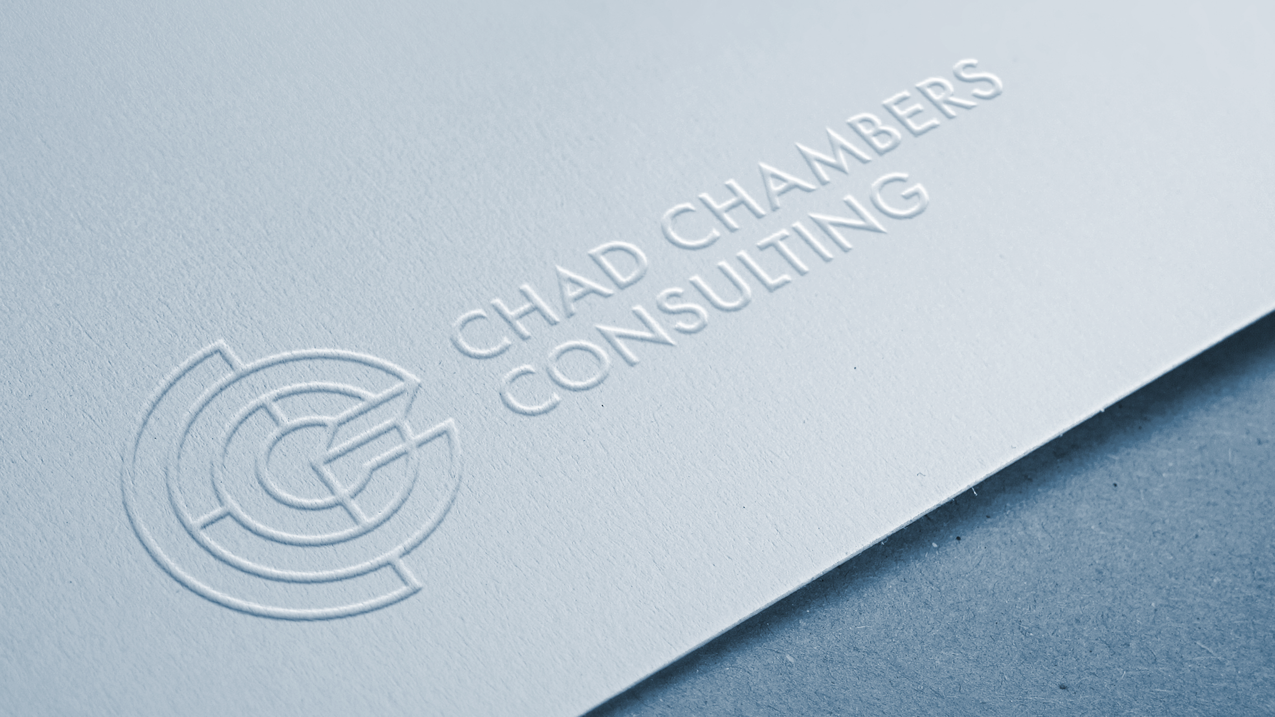 Monochromatic embossed mockup of the Chad Chambers Consulting primary logo on white textured recycled paper.