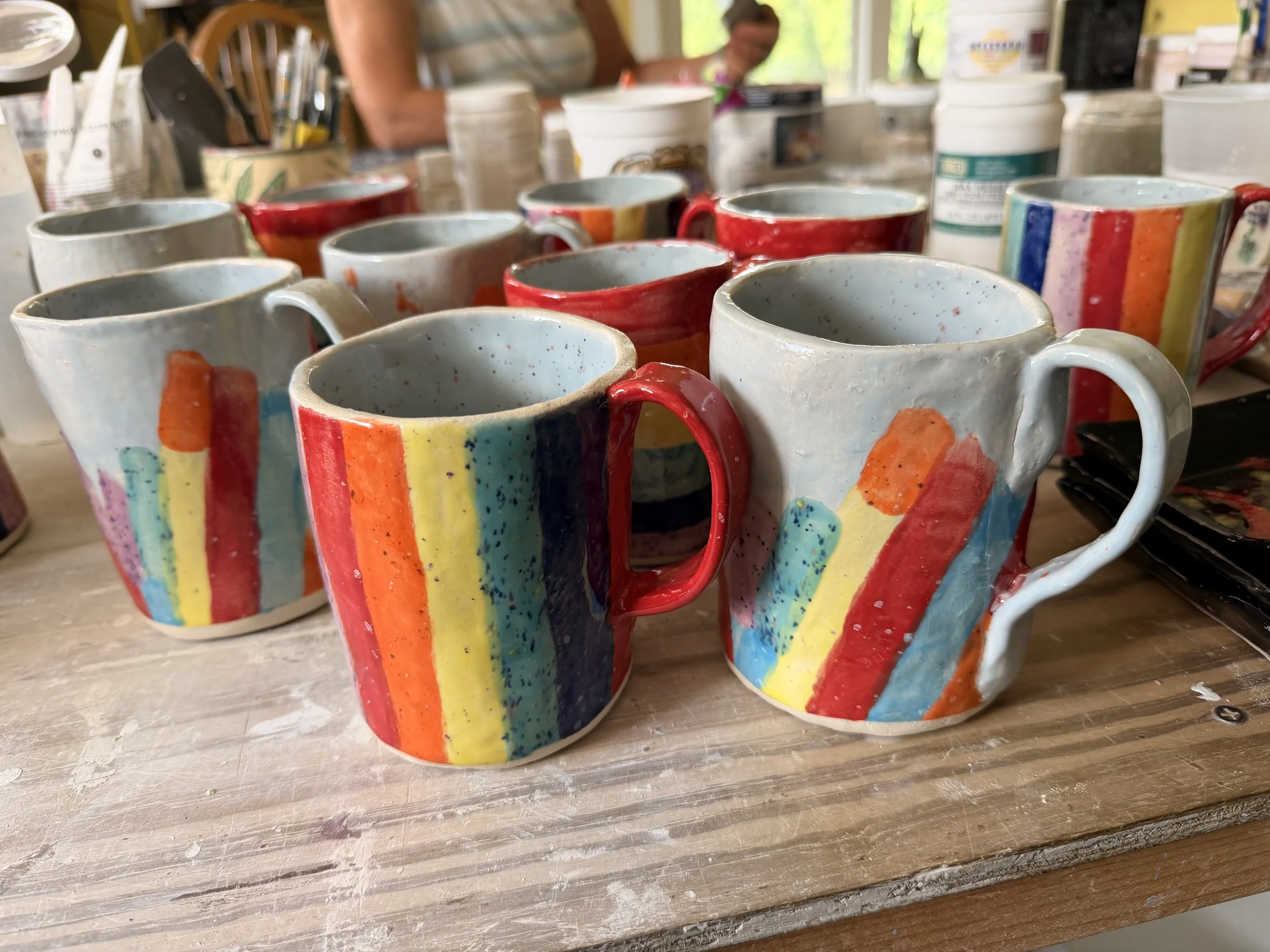 Variety of Rainbow Mug Styles on a Table Fresh from the Kiln.