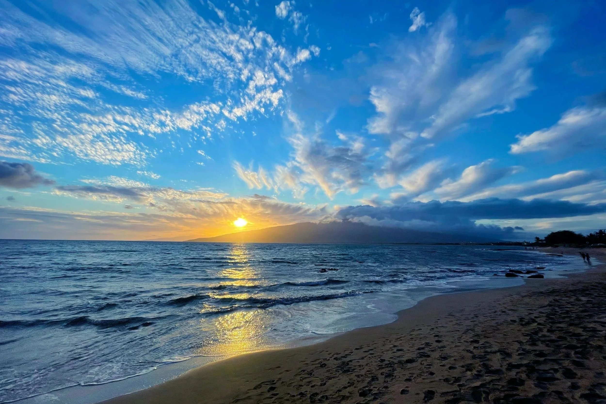 Vibrant beach sunset with golden light reflecting on the waves and dramatic blue skies, symbolizing peace, renewal, and Habits for the Spirit.