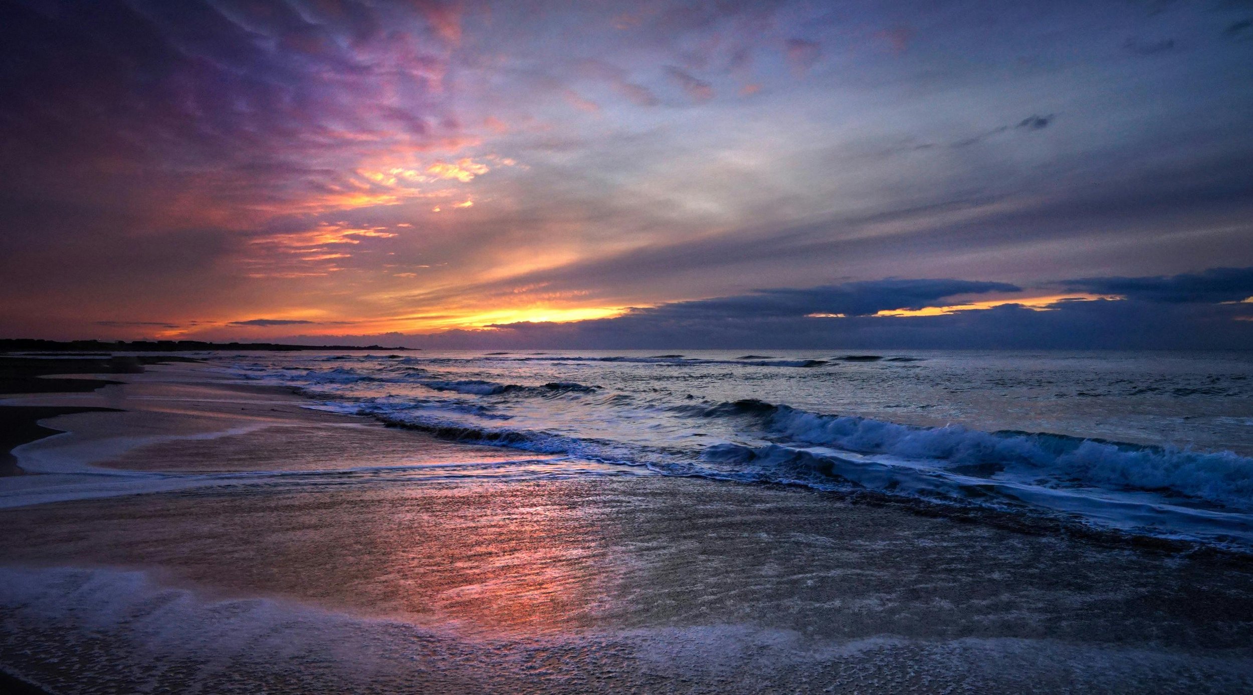 Peaceful ocean waves rolling onto the shore at sunset, with purple and orange hues across the sky and water, reflecting a sense of stillness and Habits for the Spirit.