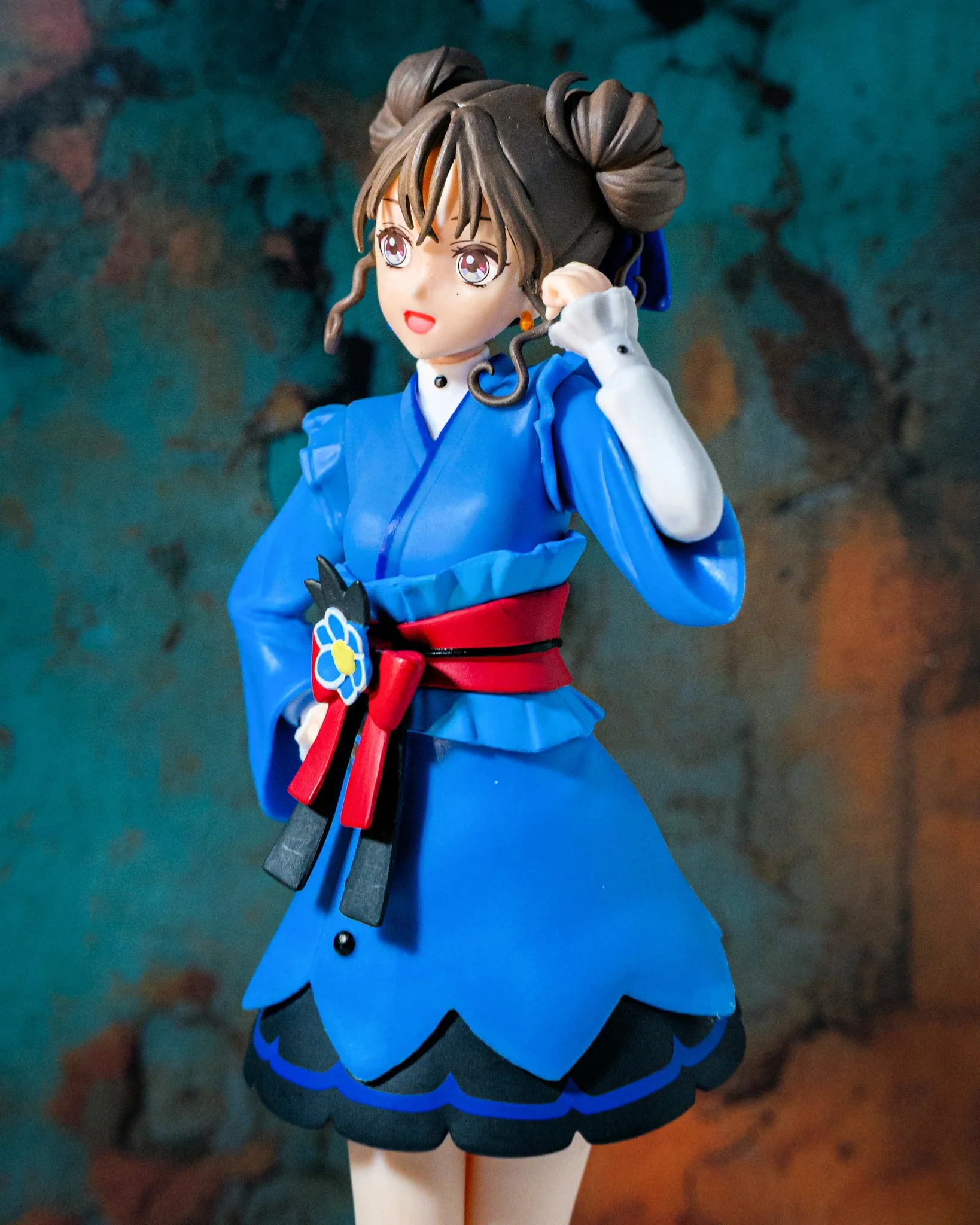 Anime-style figure of a brown-haired girl wearing a blue dress, posed simply against a clean, minimal background with even lighting.