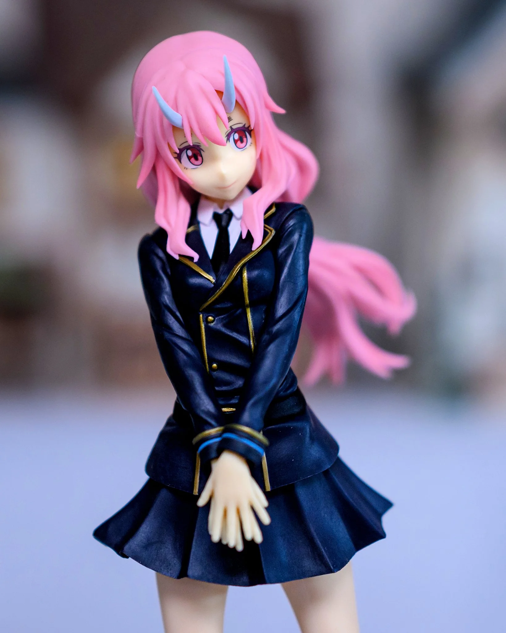 Anime-style figure of a demon girl posed in front of a softly blurred outdoor background, with shallow depth of field isolating the subject.