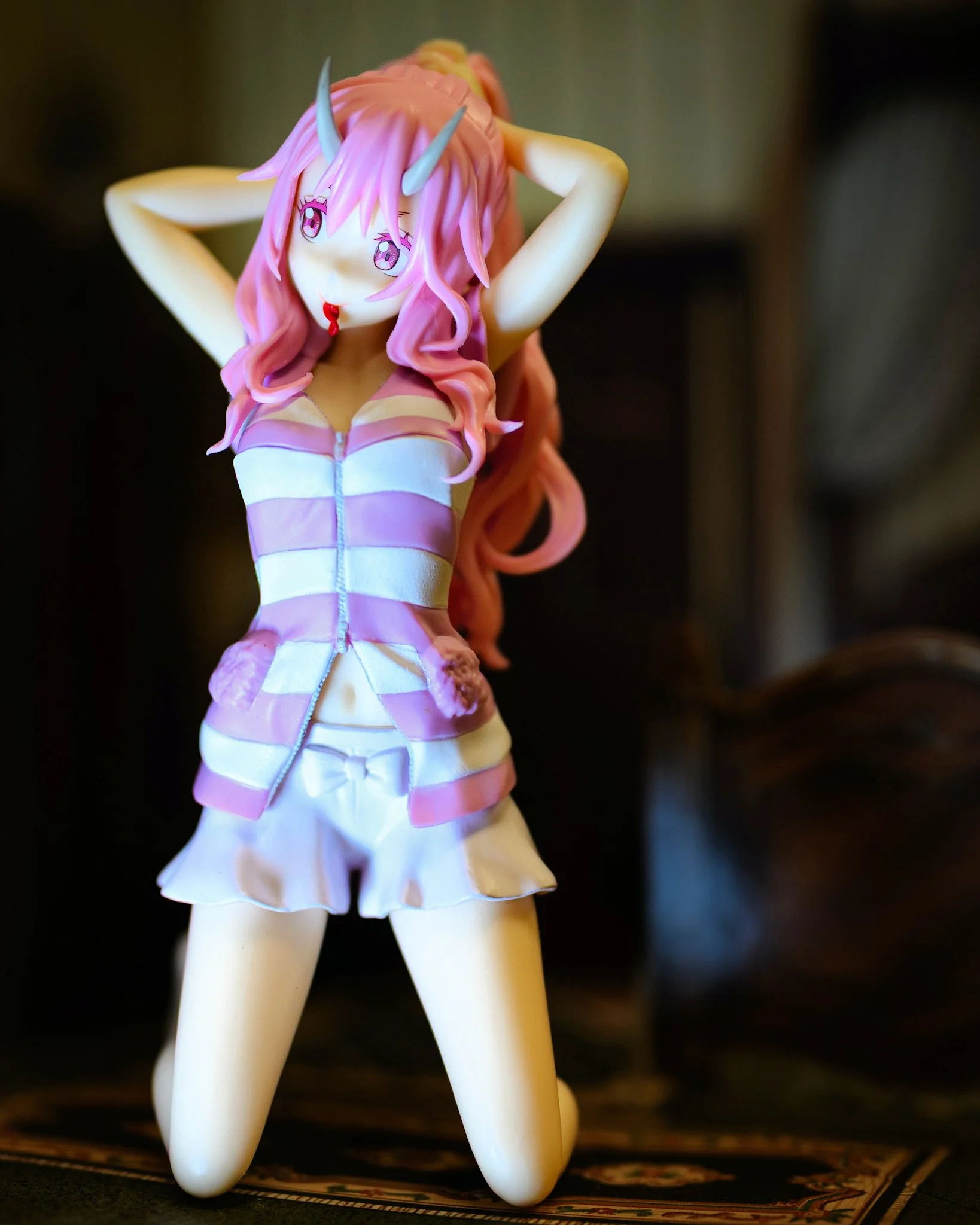 Anime-style figure of a demon girl adjusting her hair, with stylized horns and a confident pose, set against a softly blurred background.