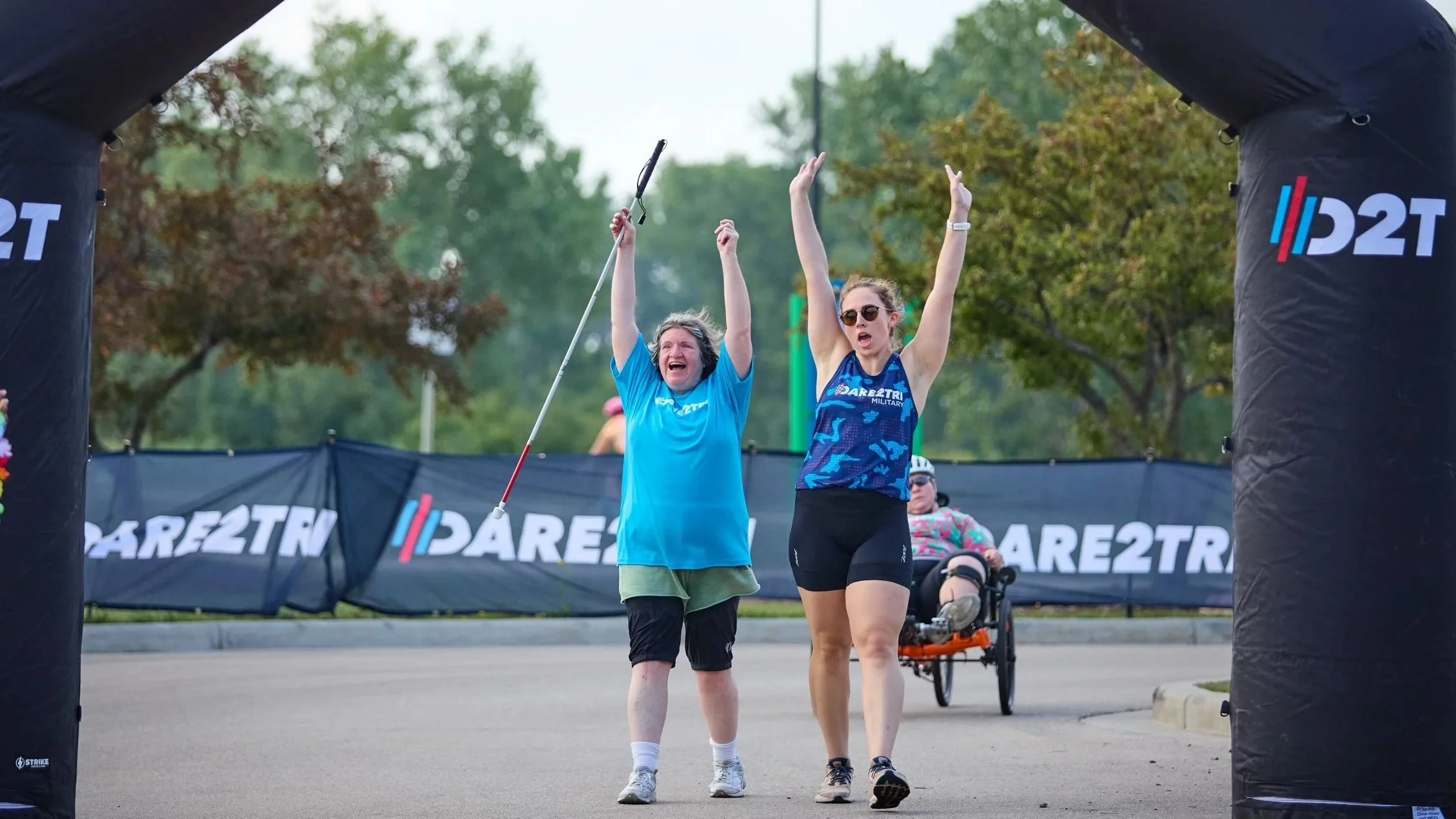 Ryan Ricker and an adaptive athlete cross a finish line