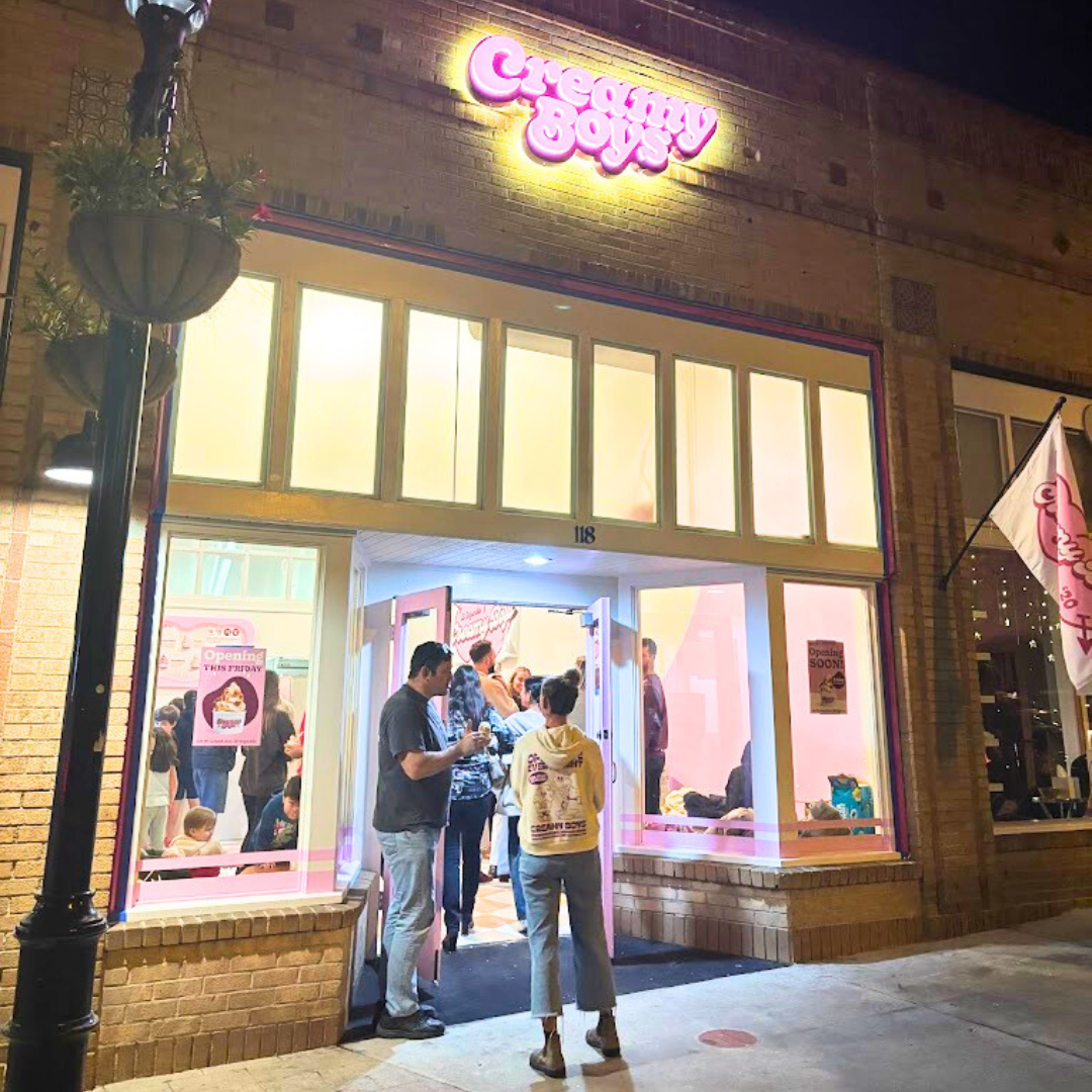 People outside the Creamy Boys ice cream shop at night with lit signage and windows.