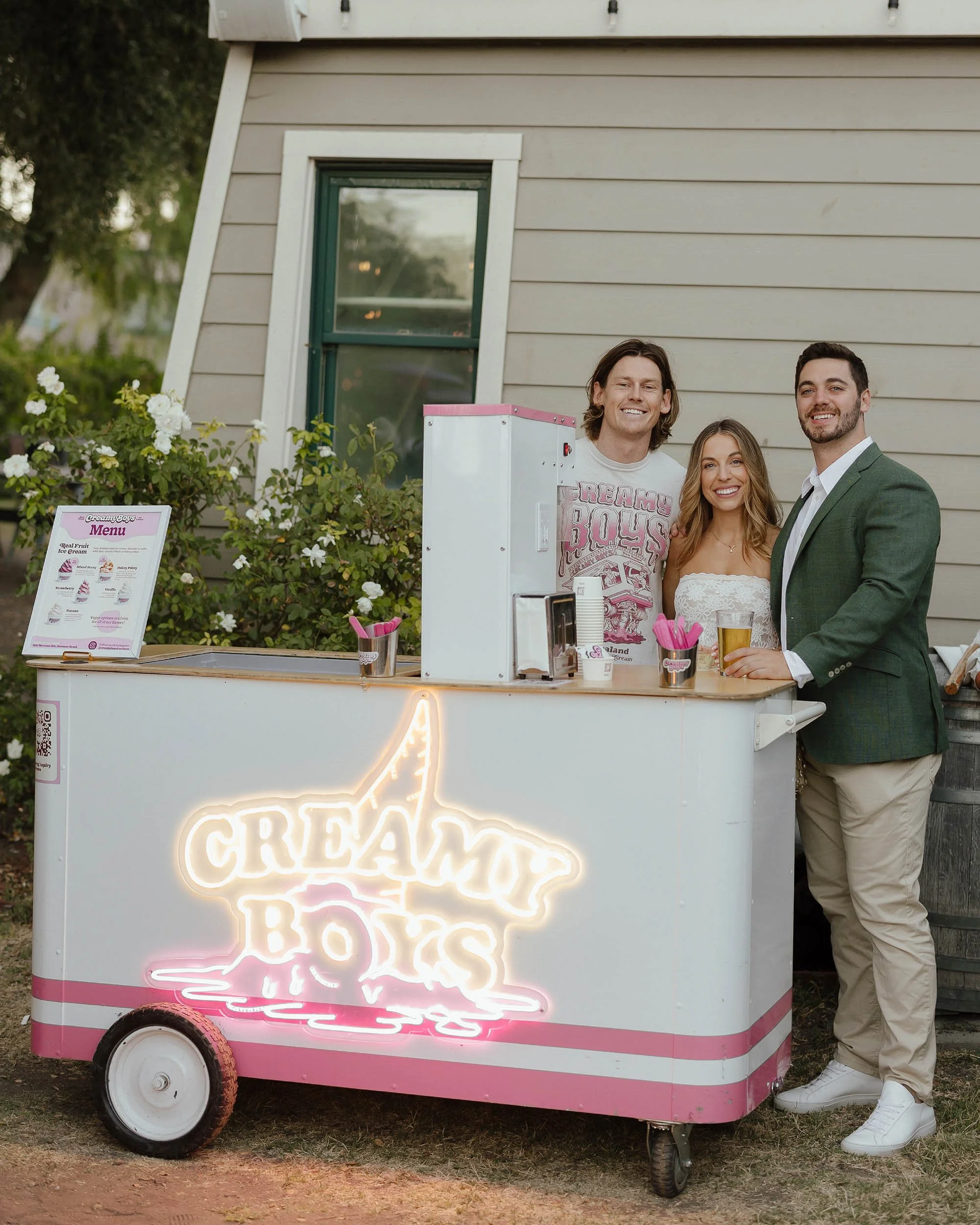 Three people standing behind Creamy Boys ice cream cart