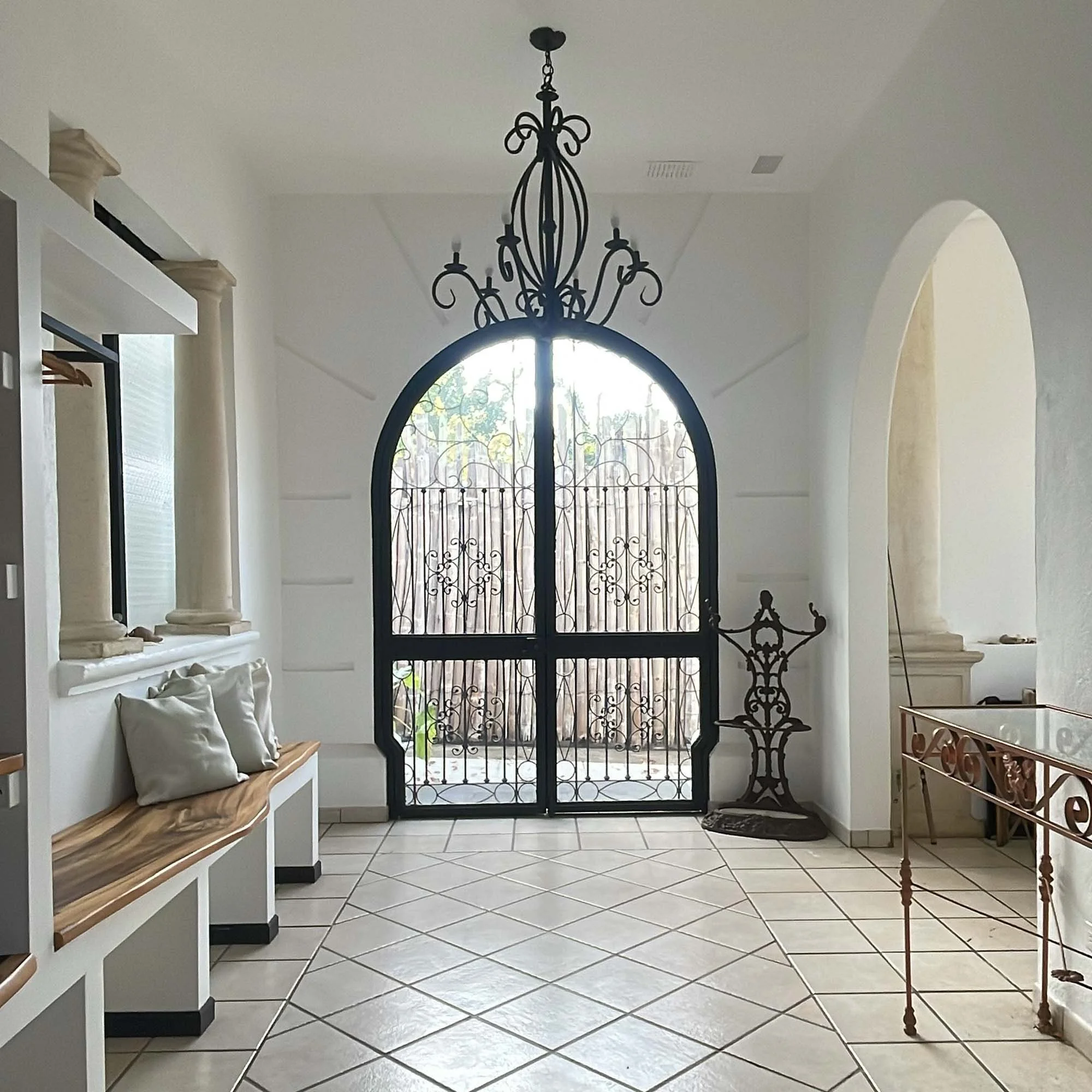 Inviting entry way to the villa in Costa Rica with gorgeous entry doors and local wood details inside and chandelier