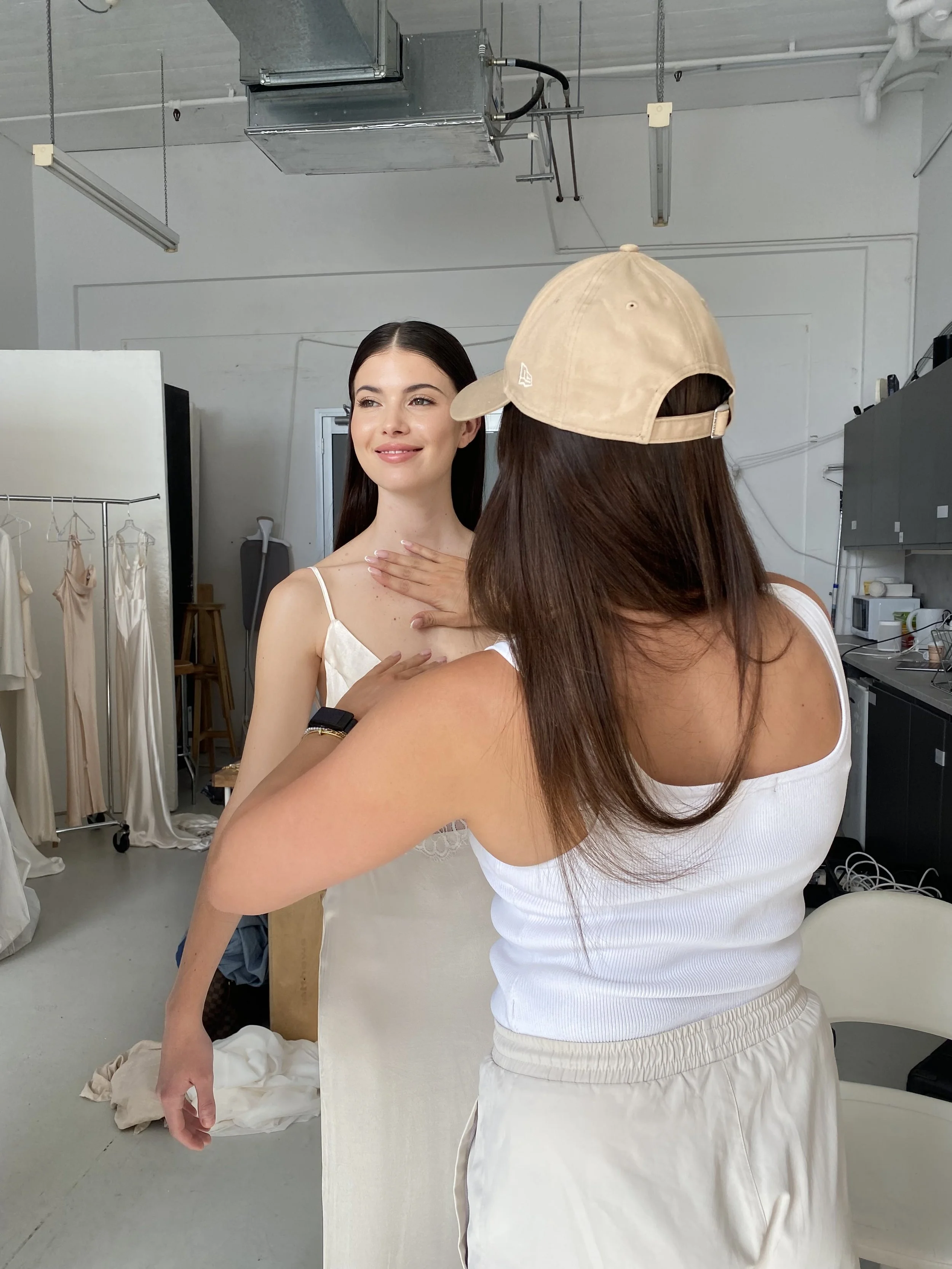 Bride in white wedding gown with women assisting her in make up.