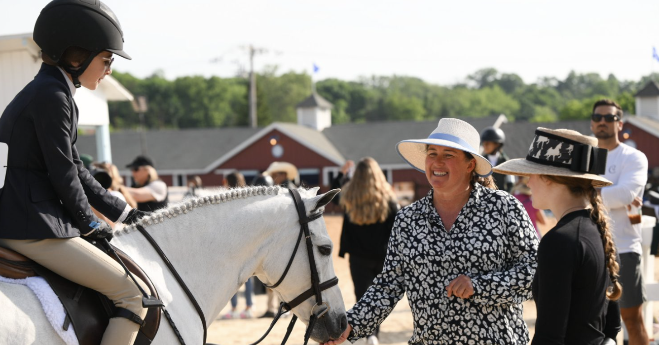Scenic landscape of a lake surrounded by rolling hills and mountains under a cloudy sky.