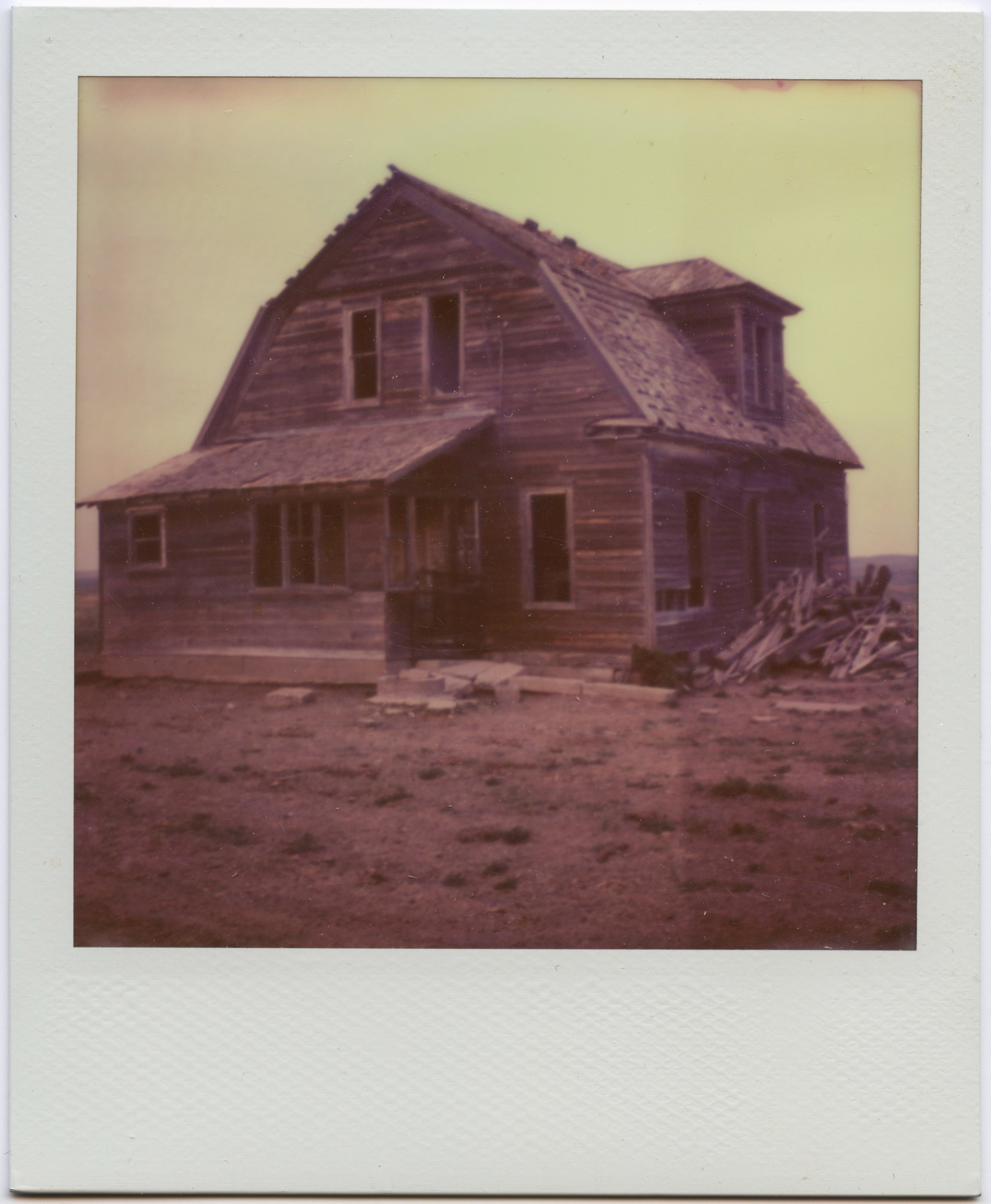 a polaroid of the exterior of an abandoned farmhouse, found in Dawson County, Nebraksa.