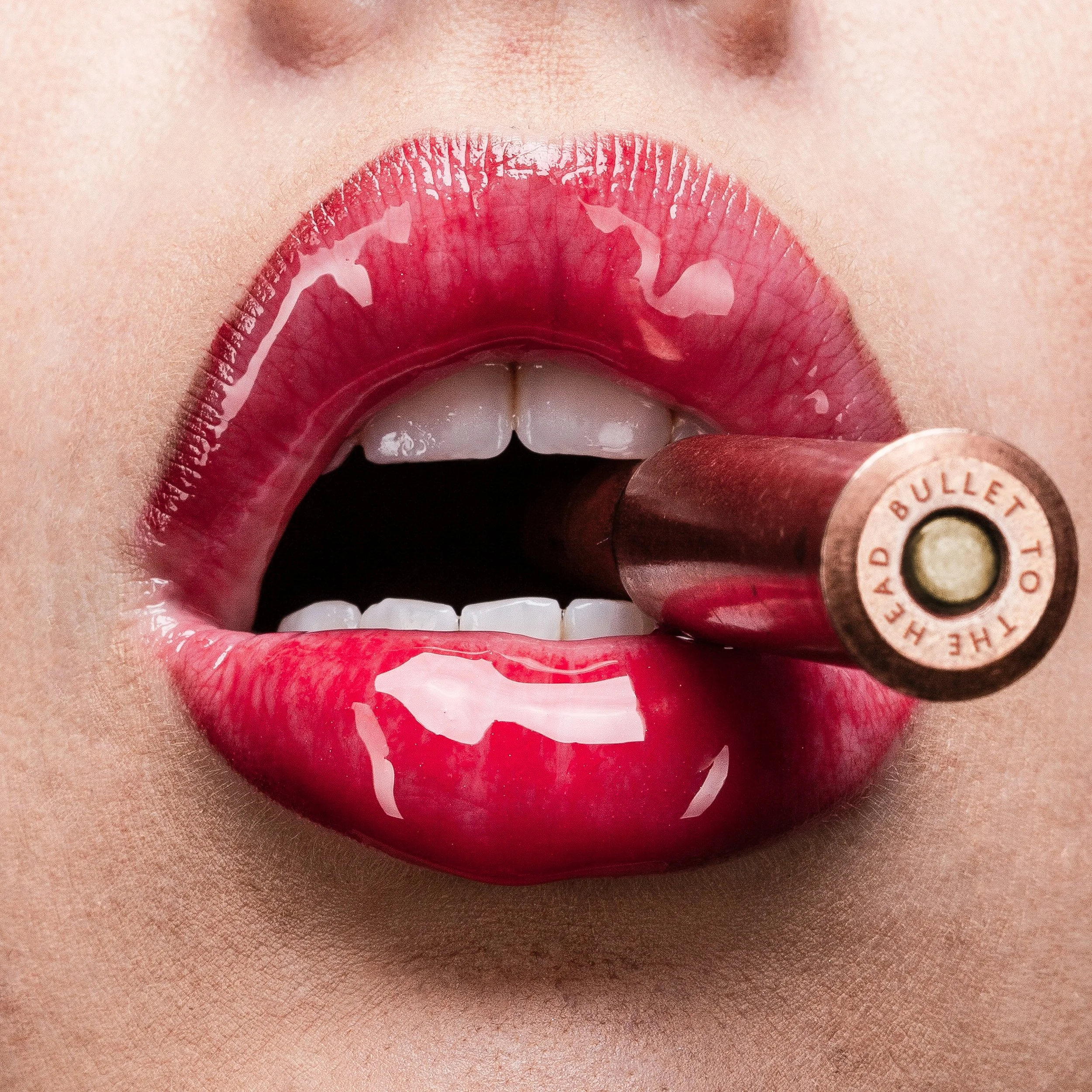 Close-up of lips with bright red lipstick and a lipstick tube near the bottom right.