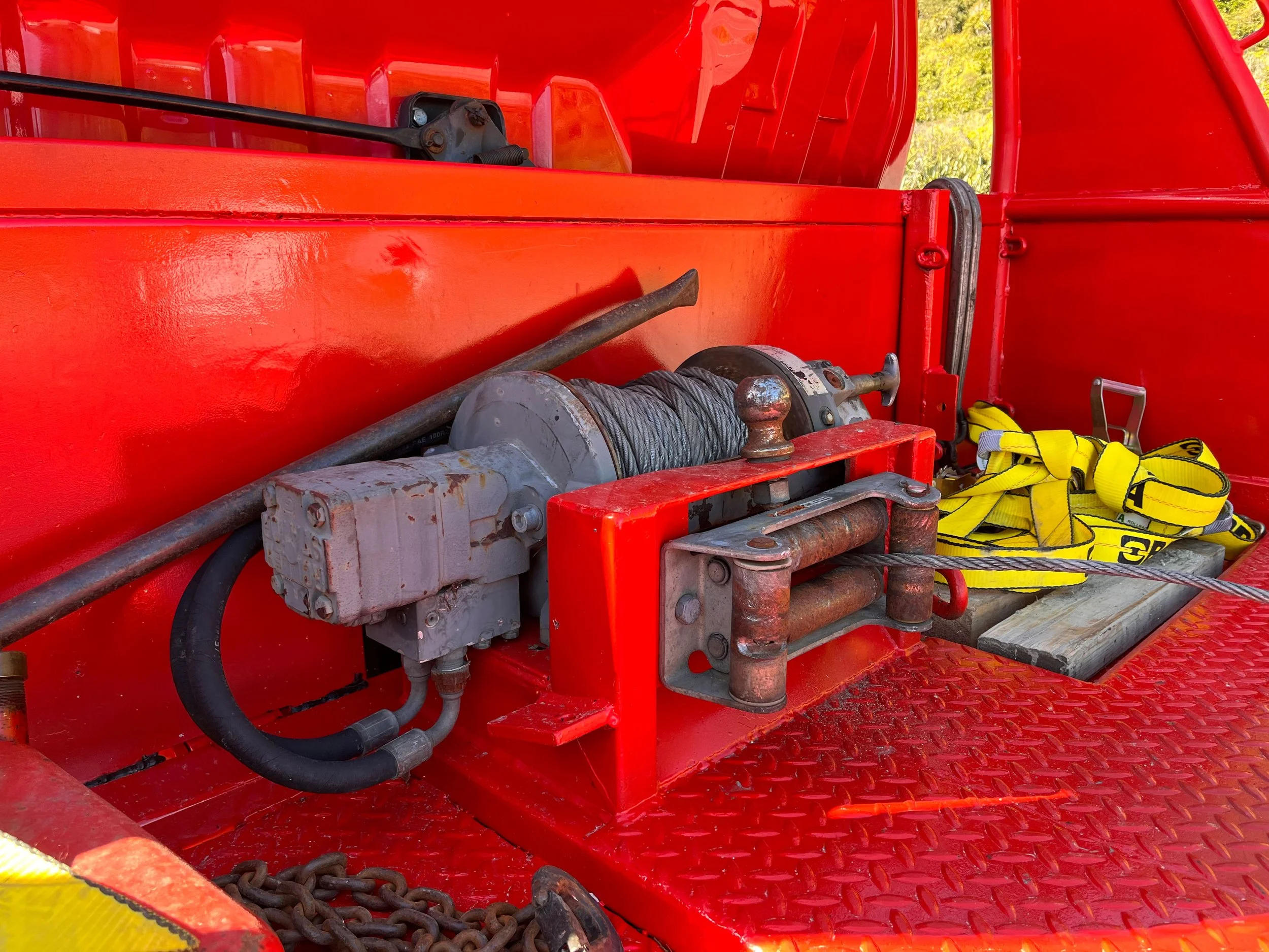 Close-up of the Buller Towing & Recovery mechanical winch with attached cable, yellow straps and chain in foreground.