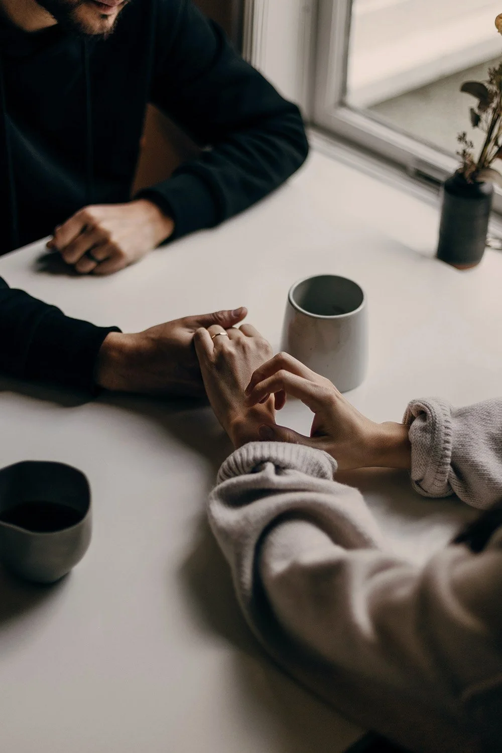 Couple gently holding hands during a quiet conversation, symbolizing connection and emotional support.