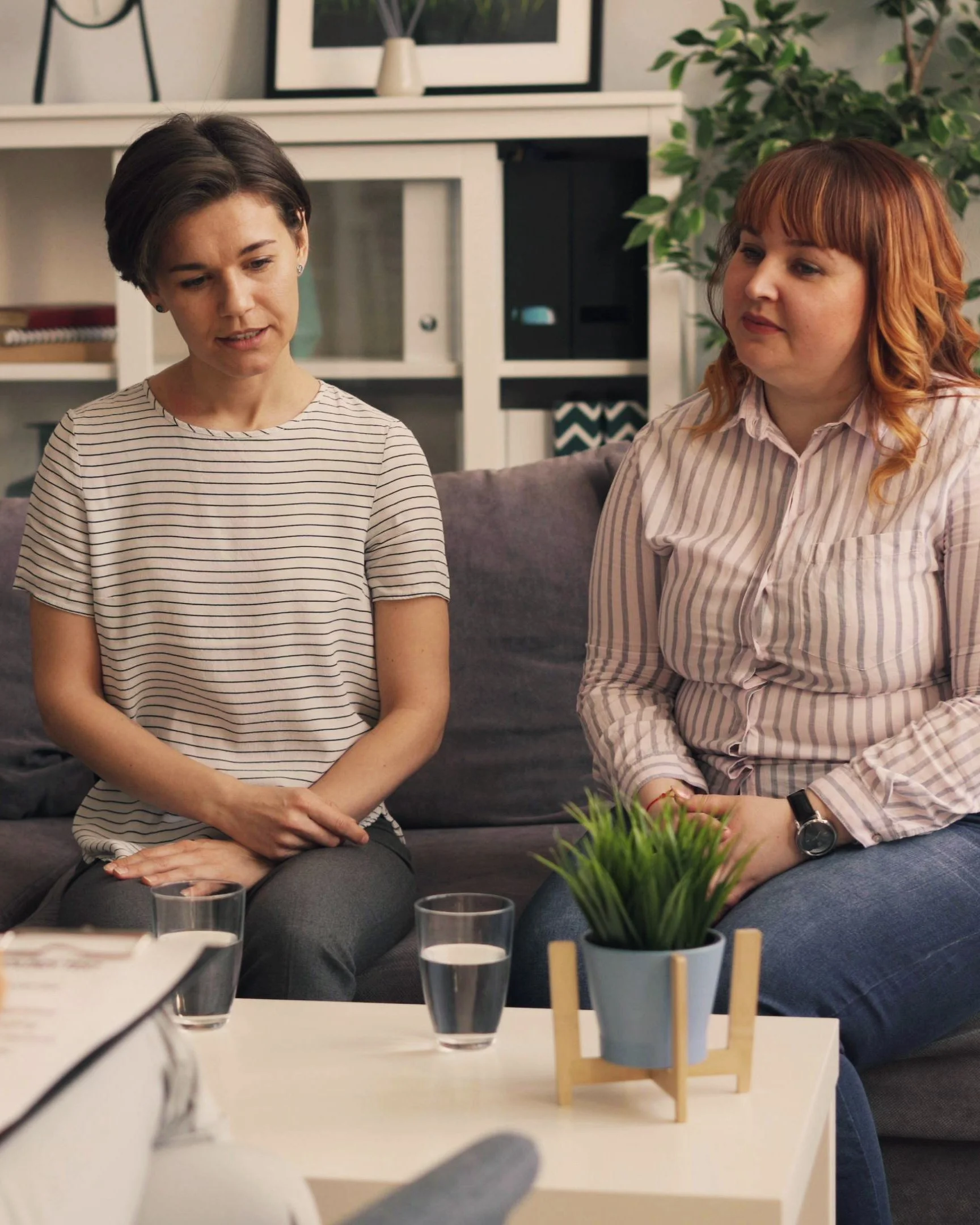 Two women sitting together in a counselling session, speaking with a therapist in a calm, supportive setting.