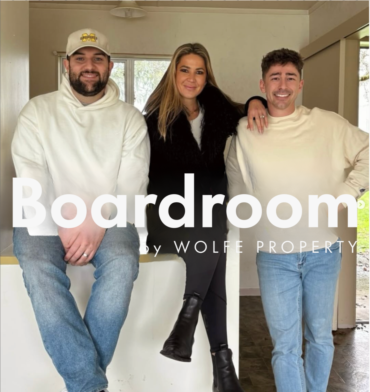 Three people standing inside a house, a woman and two men, smiling at the camera.