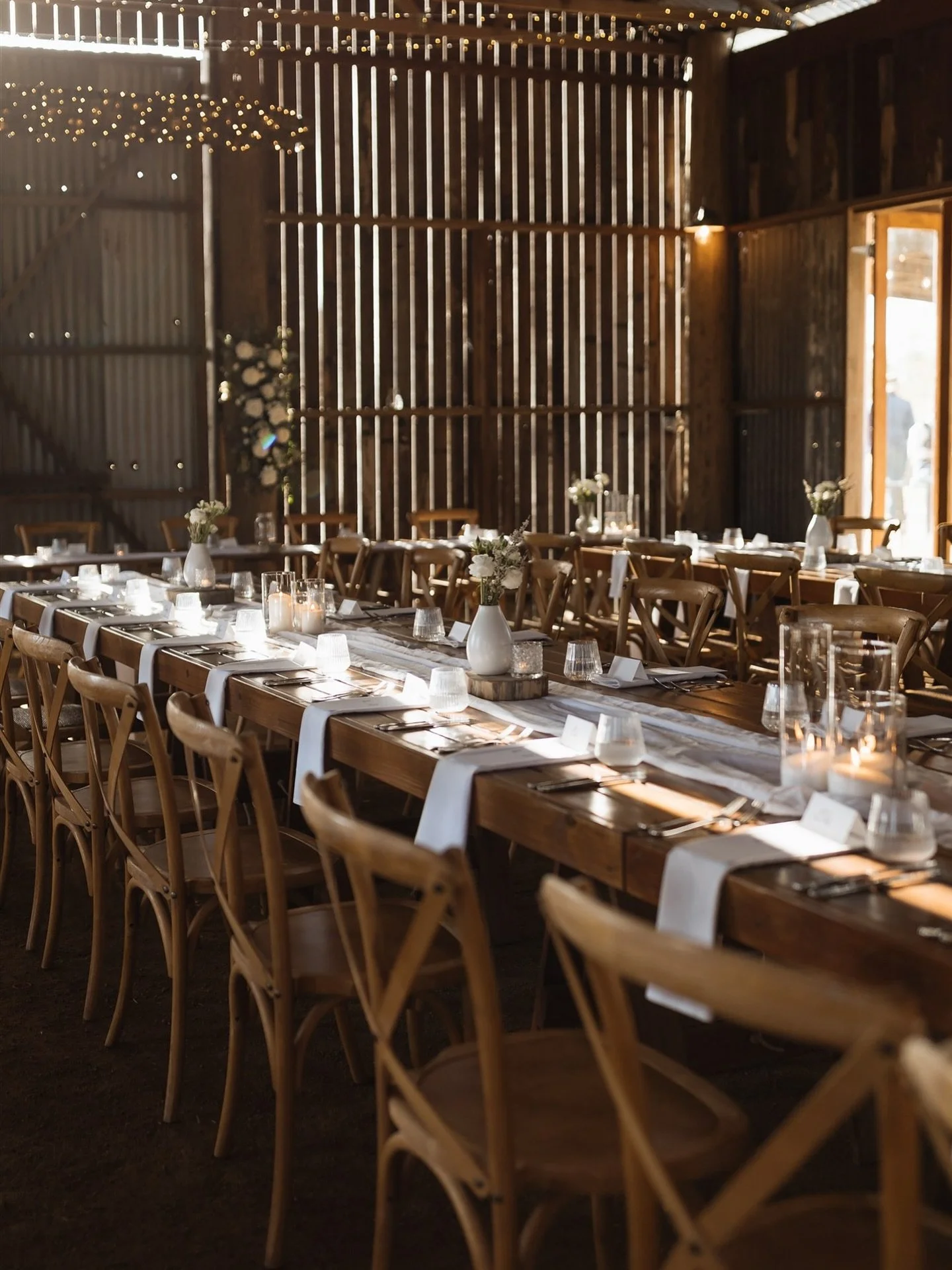 Golden light spilling across timber tables, soft candlelight dancing through the barn, and the hum of anticipation just before guests take their seats.

A beautifully pared-back country setting; warm, refined, and effortlessly elegant.