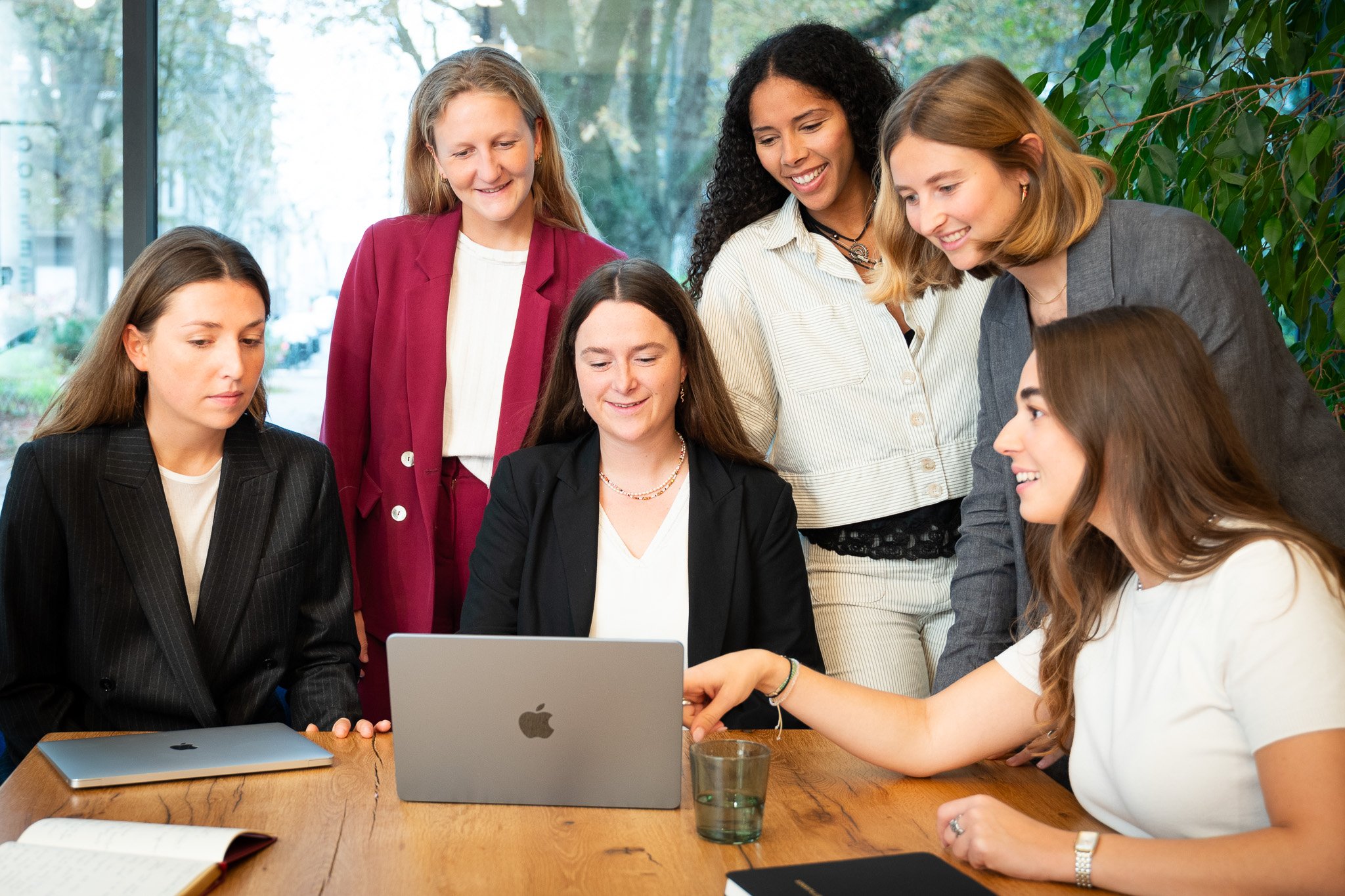 picture of girls working together around a wooden table and laptops