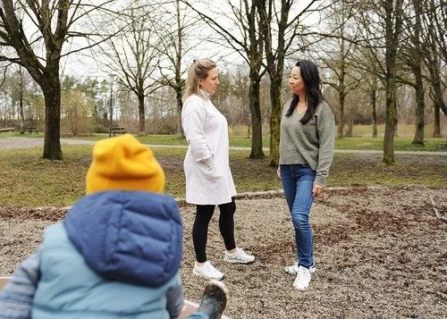 Zwei Frauen unterhalten sich in der Natur, vorne sieht man von hinten ein kleines Kind