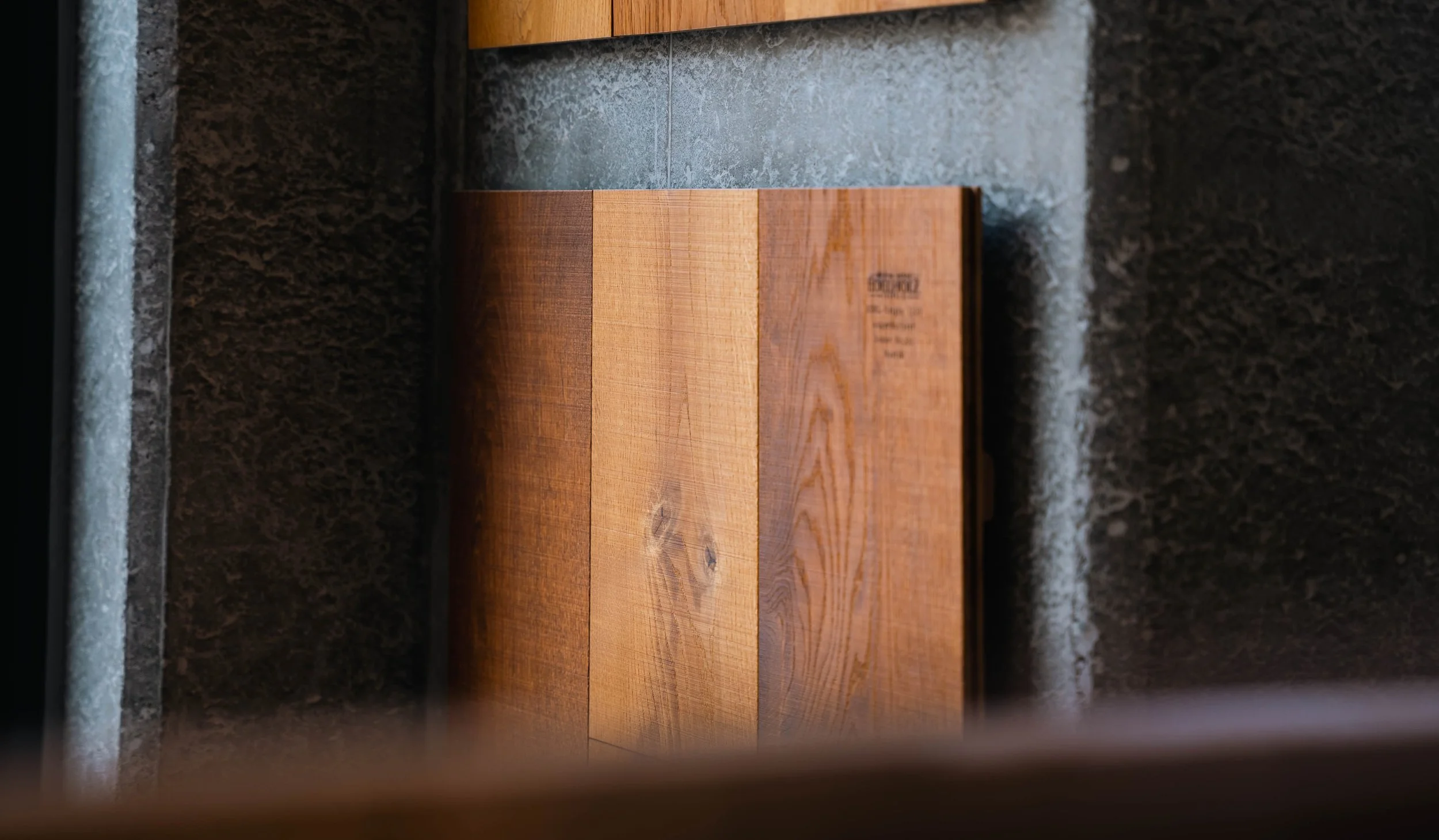 Close-up of a wooden box or panel against a dark wall with textured stone surface in the background.
