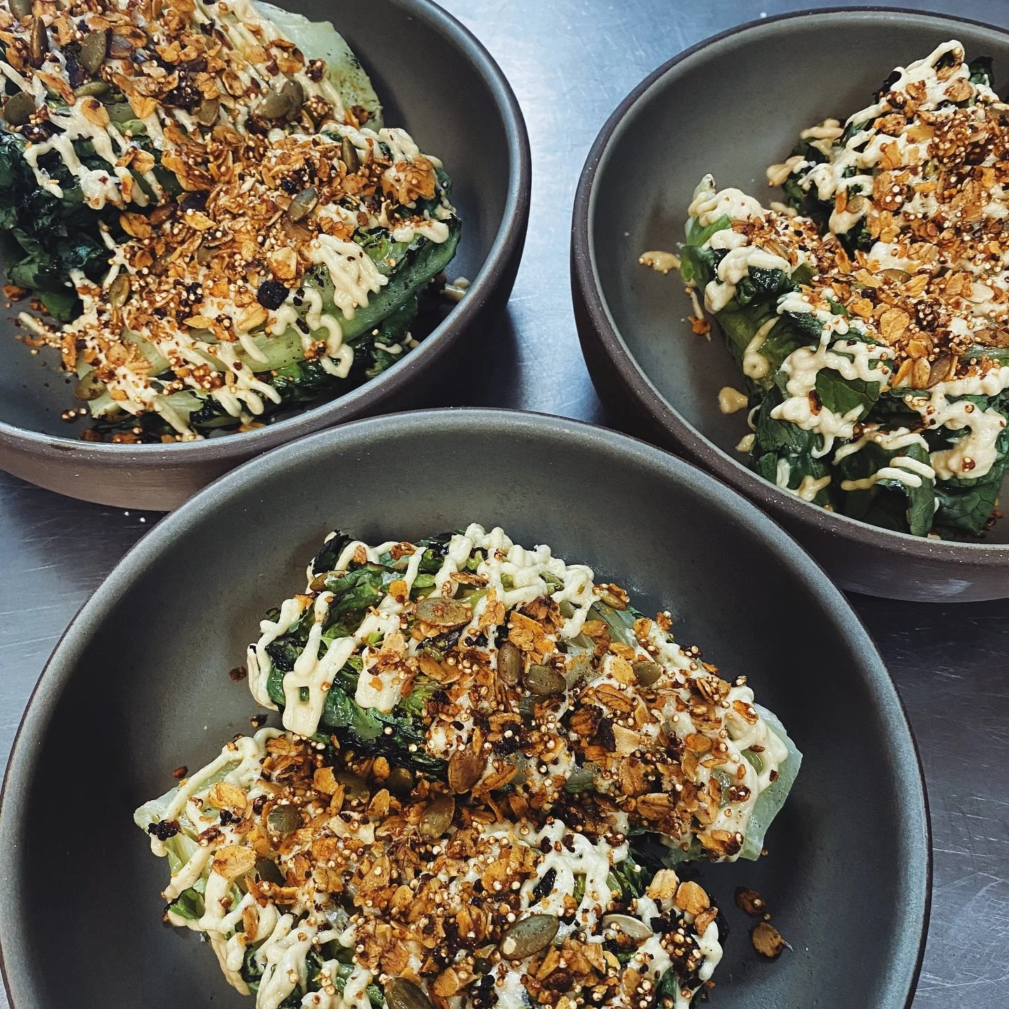 Our Caesar got a little summer makeover! Now featuring locally grown little gem lettuces, grilled, and topped with our vegan cashew dressing and spicy granola. Pair with our homemade focaccia and crispy chicken paillard for the perfect summer night m