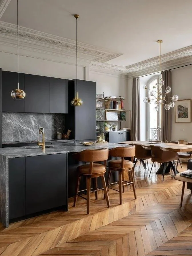 Cuisine moderne noire avec jolie parquet ancien au sol.