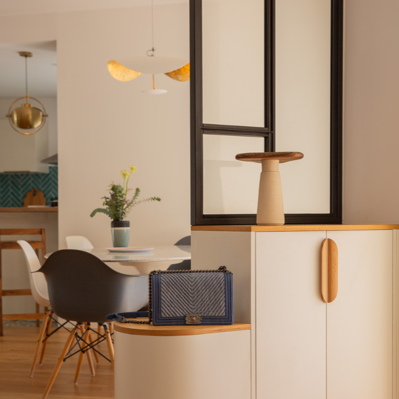 Espace entrée avec un meuble où l'on retouve des poignées de porte en bois.