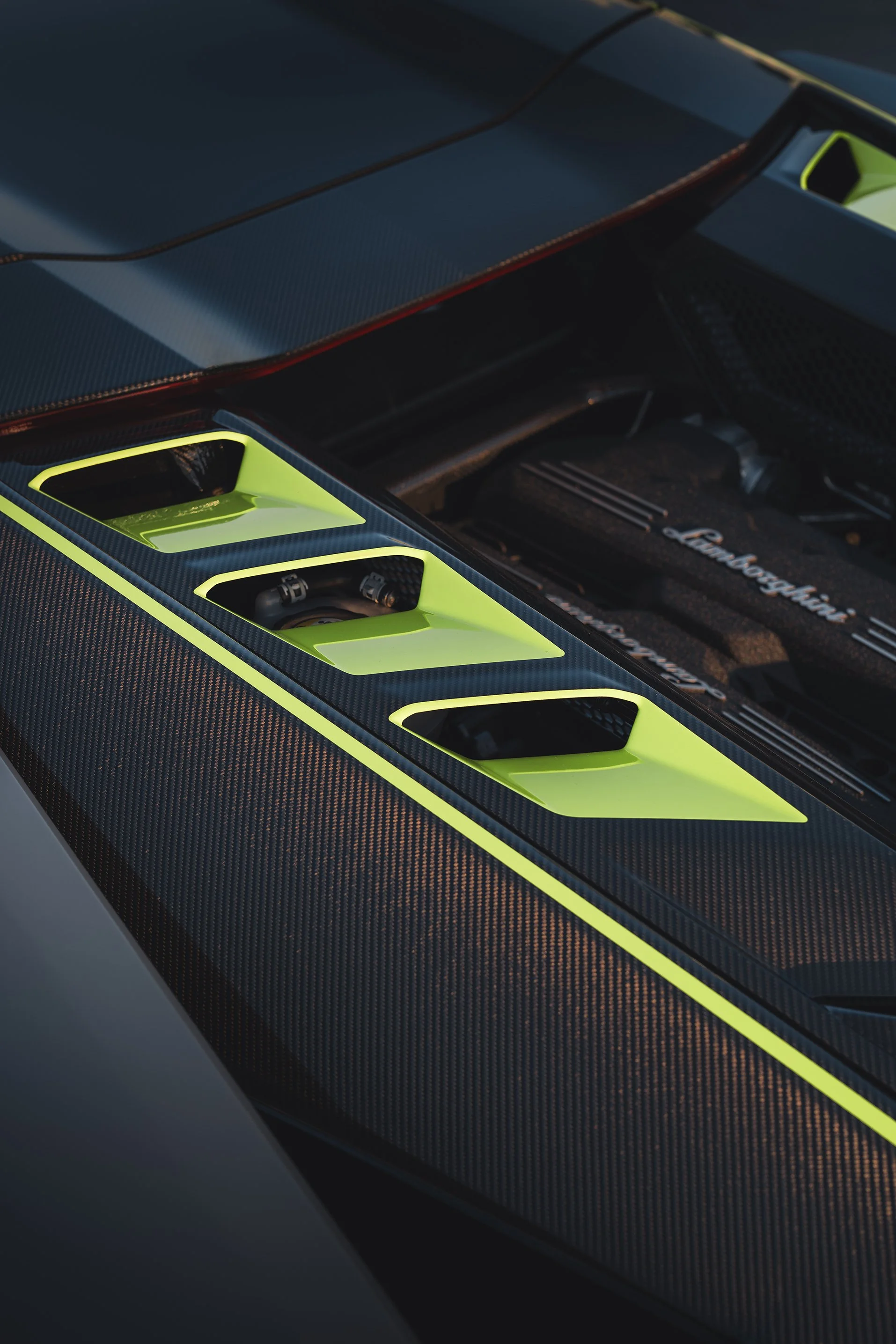 Close-up of a high-performance car engine with carbon fiber detailing and lime green accents.