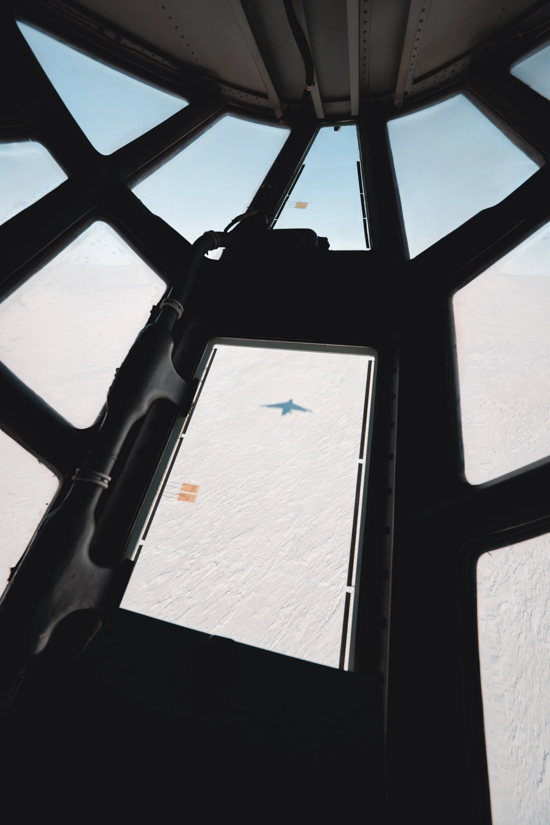 View from inside an aircraft cockpit showing the aircraft's shadow on the clouds below.