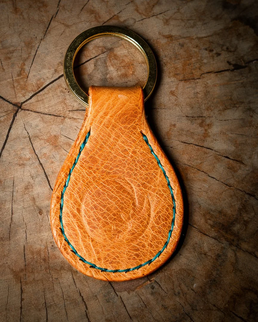 Leather and brass keychain with turquoise thread.
