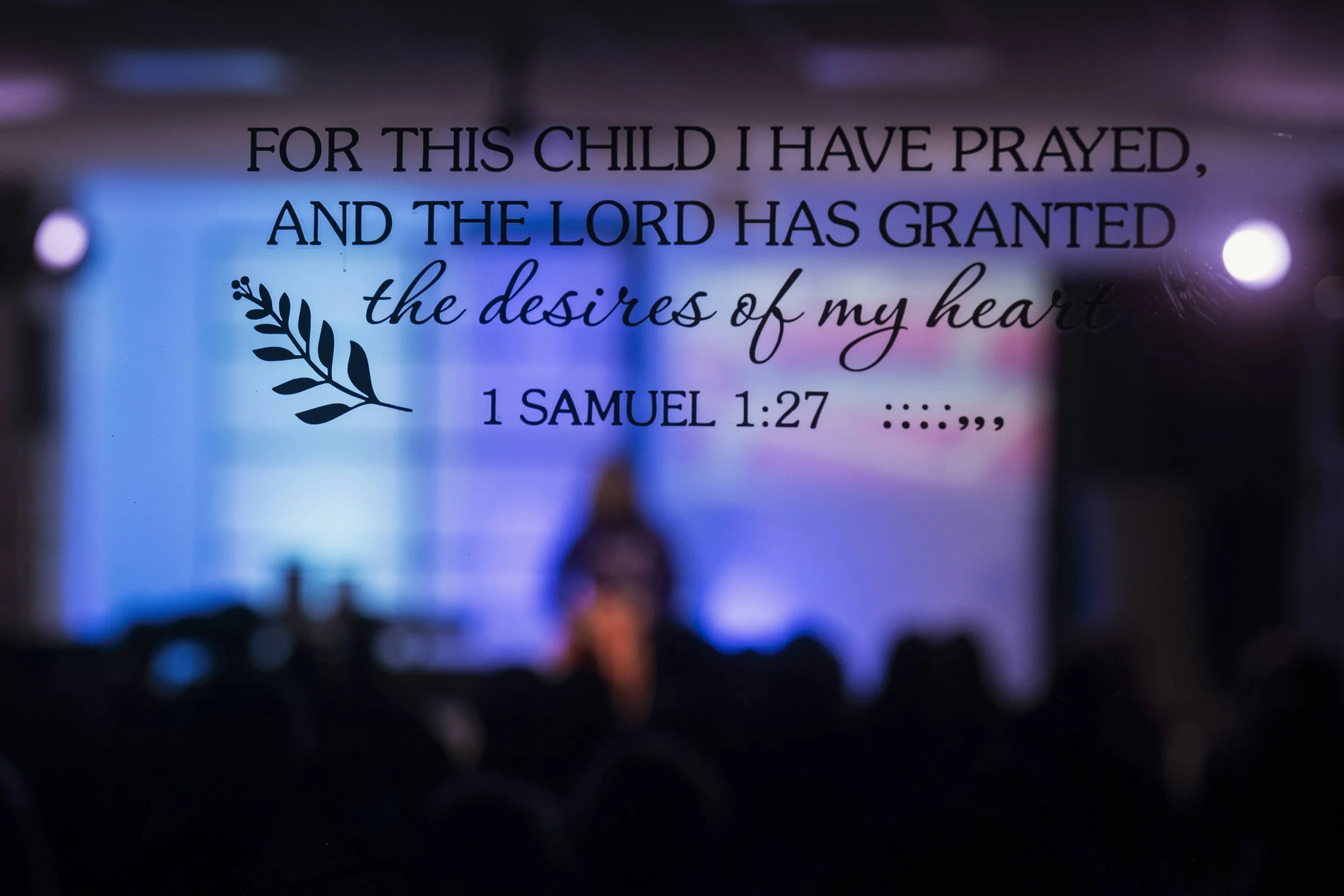 A worship screen displays the words “For This Child I Have Prayed” during a church service. Online Christian counseling supports healing so motherhood is led by faith instead of fear.