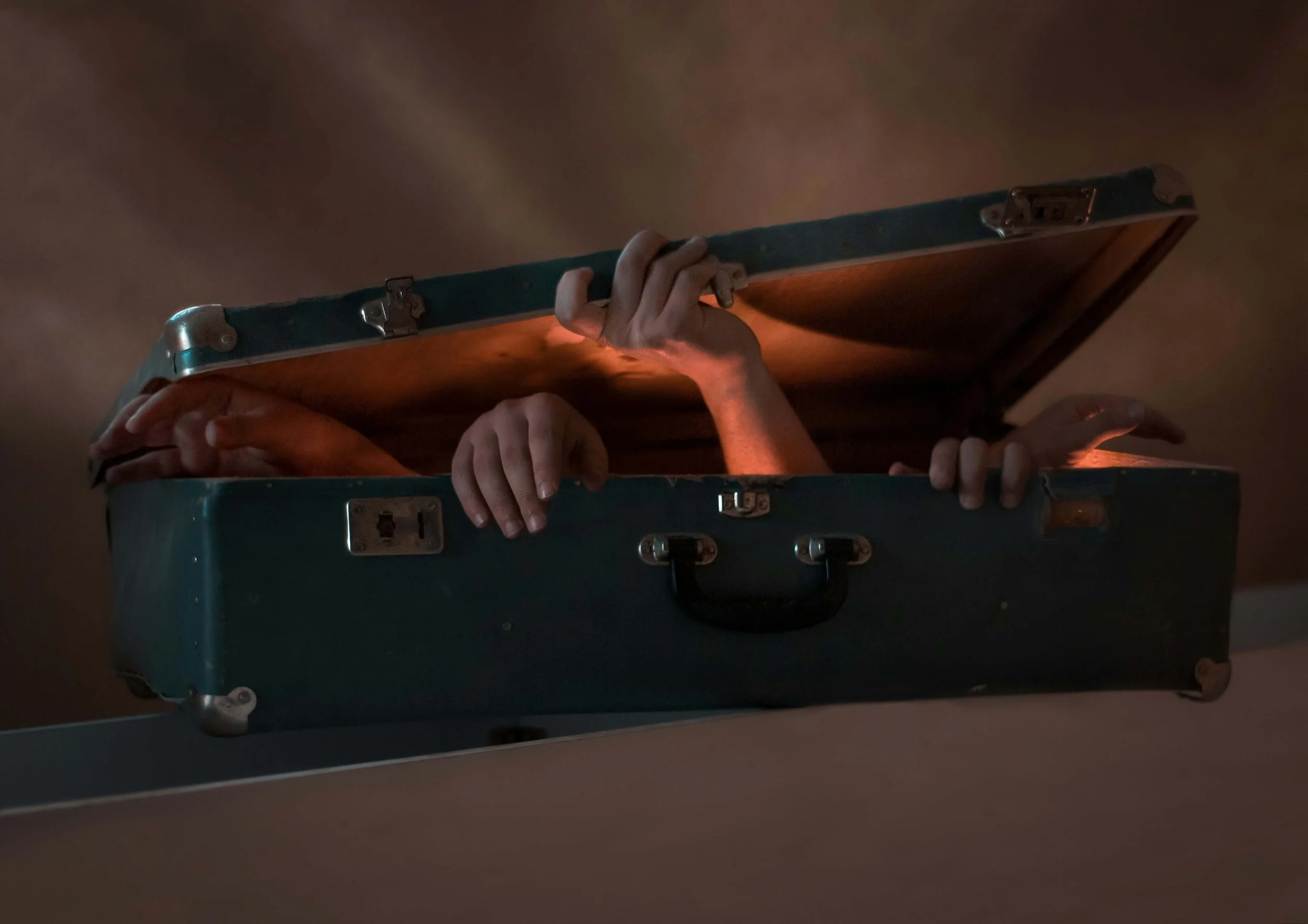 An overstuffed suitcase with hands trying to escape represents the emotional weight of unresolved trauma. Childhood trauma therapy in Columbus, OH, can help you process painful experiences.