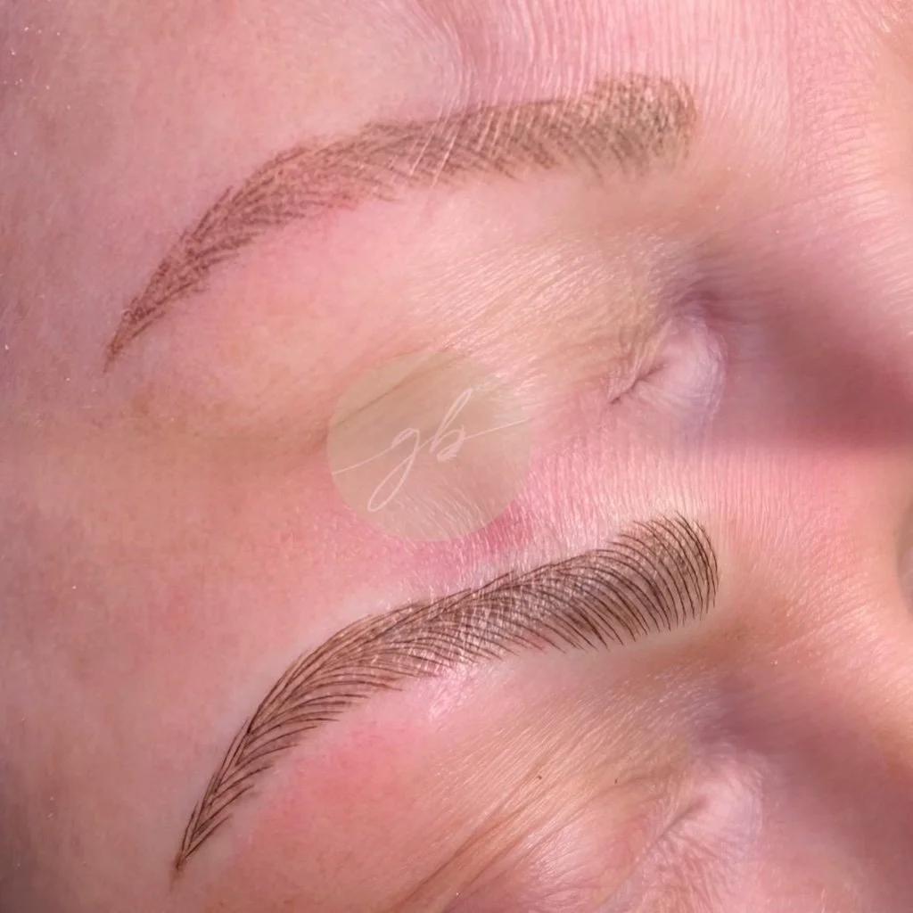 Close-up of a person's closed eyes showing newly microbladed eyebrows with fine, hair-like strokes for a natural look.