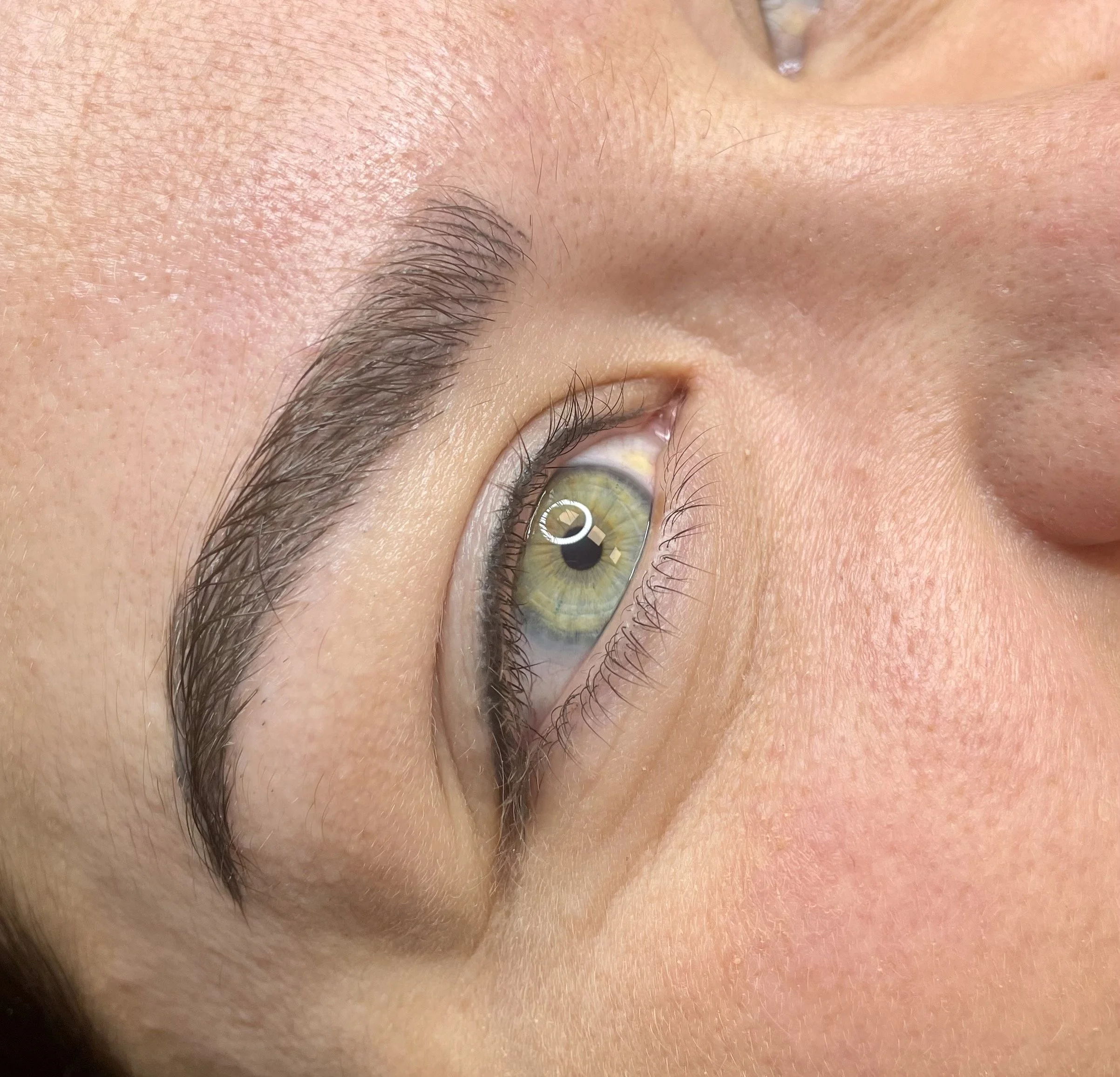 Close-up of a person's face, emphasizing the eye, eyebrow, and skin texture.