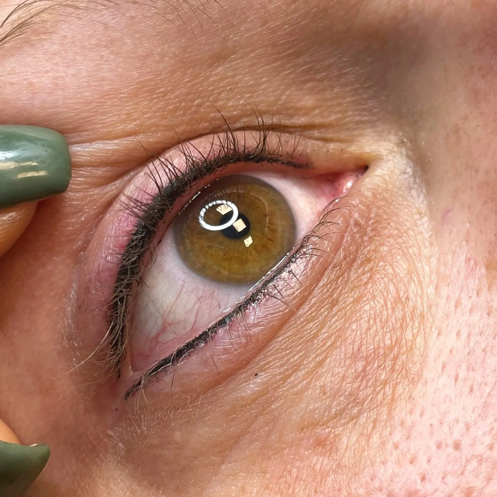 Close-up of a human eye, showing brown iris, eyelashes, and surrounding skin.