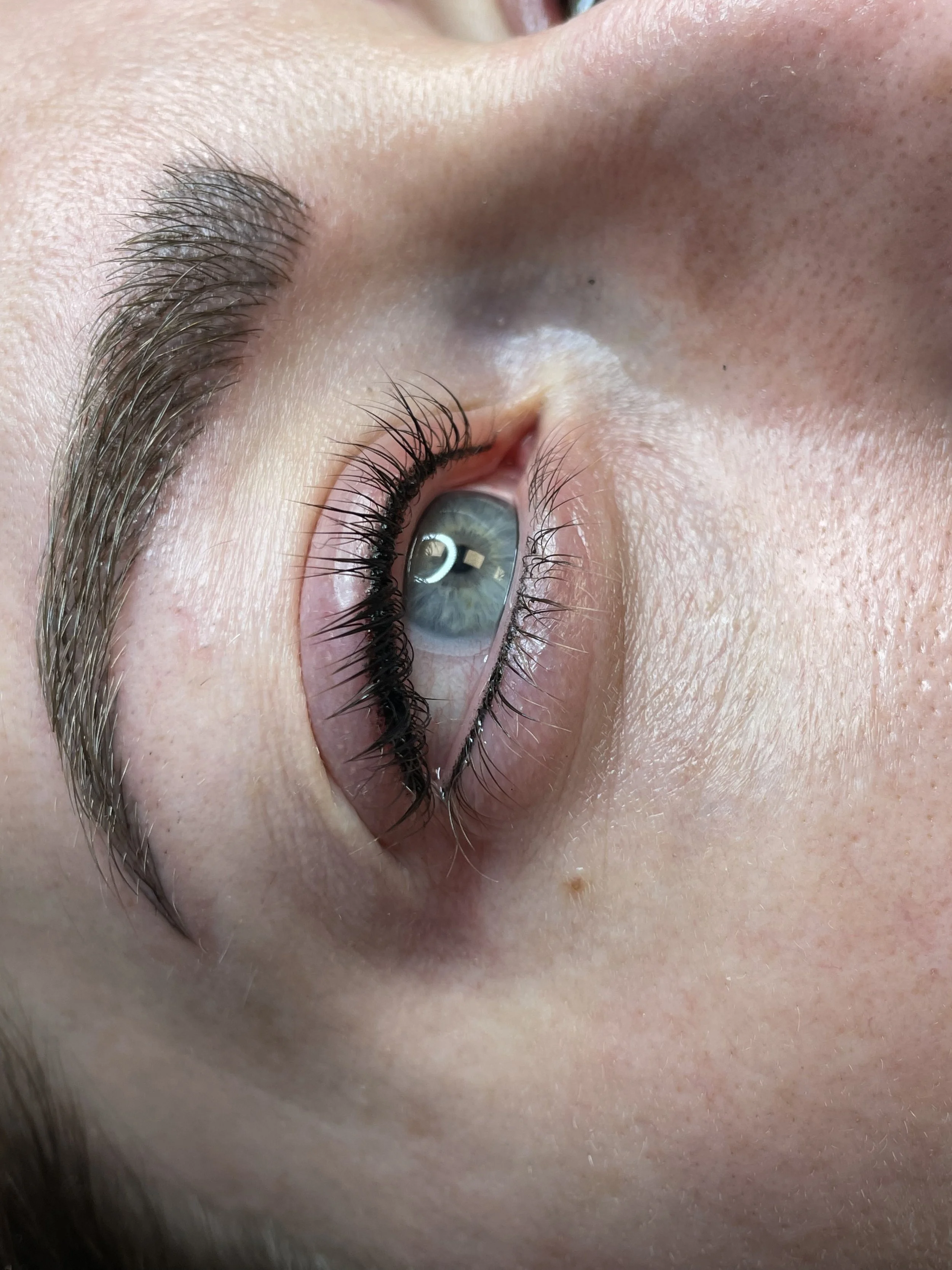 Close-up of a person's eye, showing blue eye color, long eyelashes, and part of the nose and eyebrow.