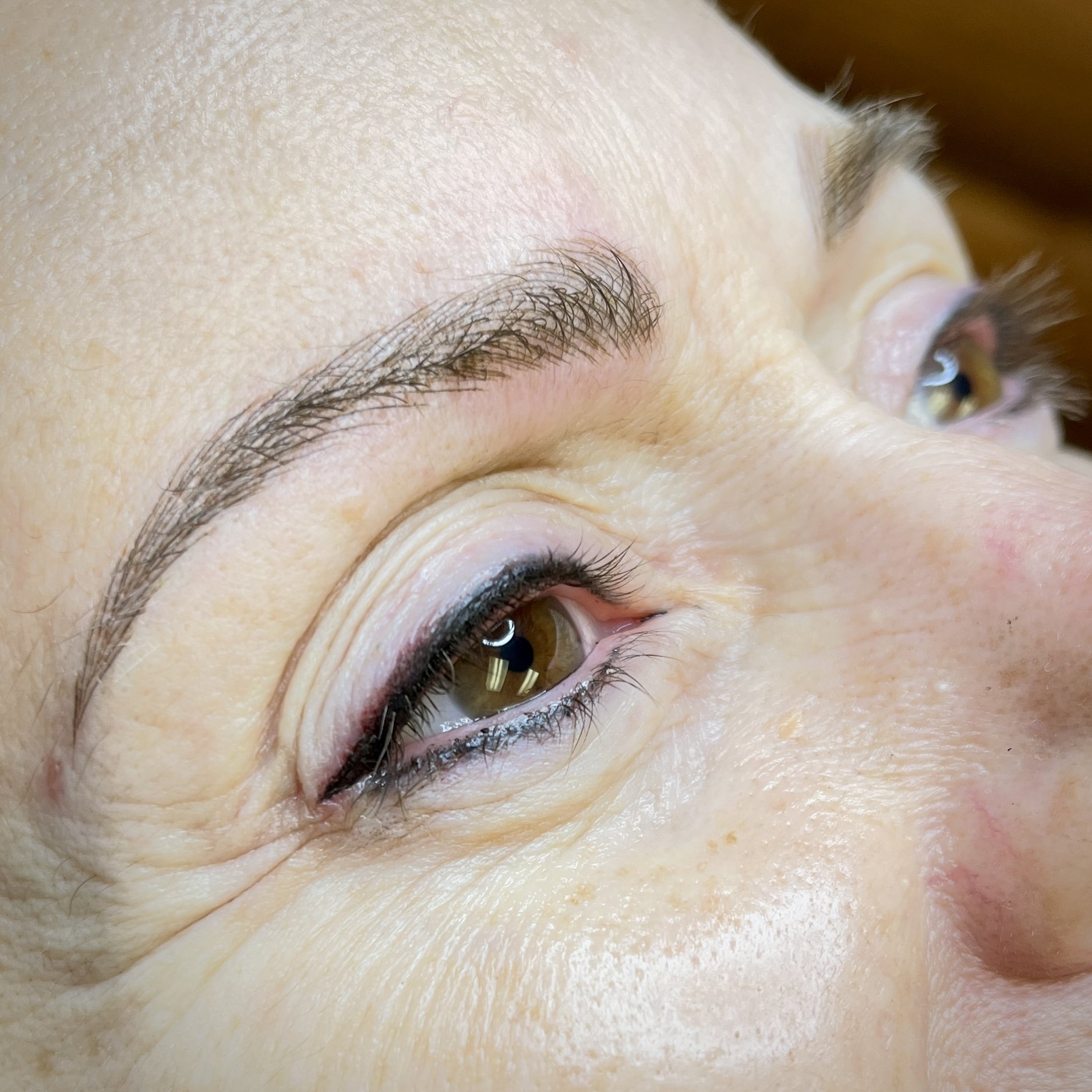 Close-up of a person's closed eyelid showing long eyelashes and light skin texture.