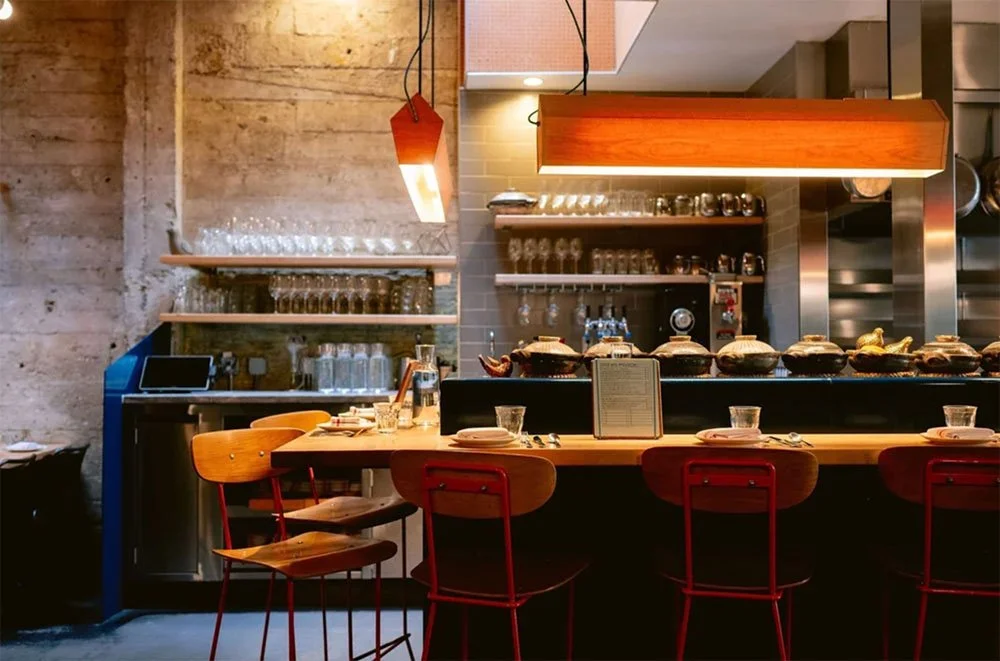State Bird's dining room showing the bar seating, lighting, glassware, and menus