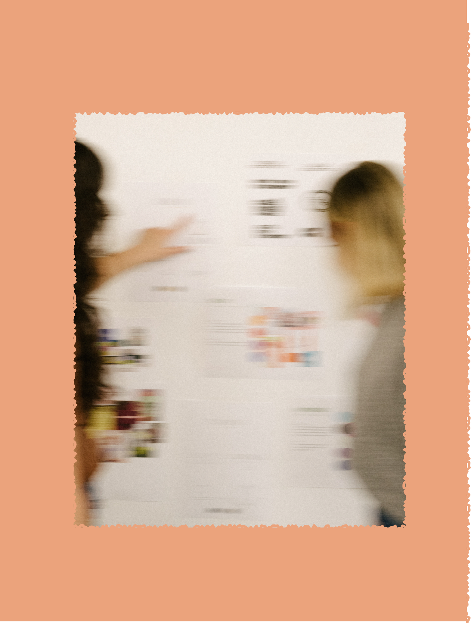 Two women discussing a presentation on a whiteboard in a classroom or conference room.