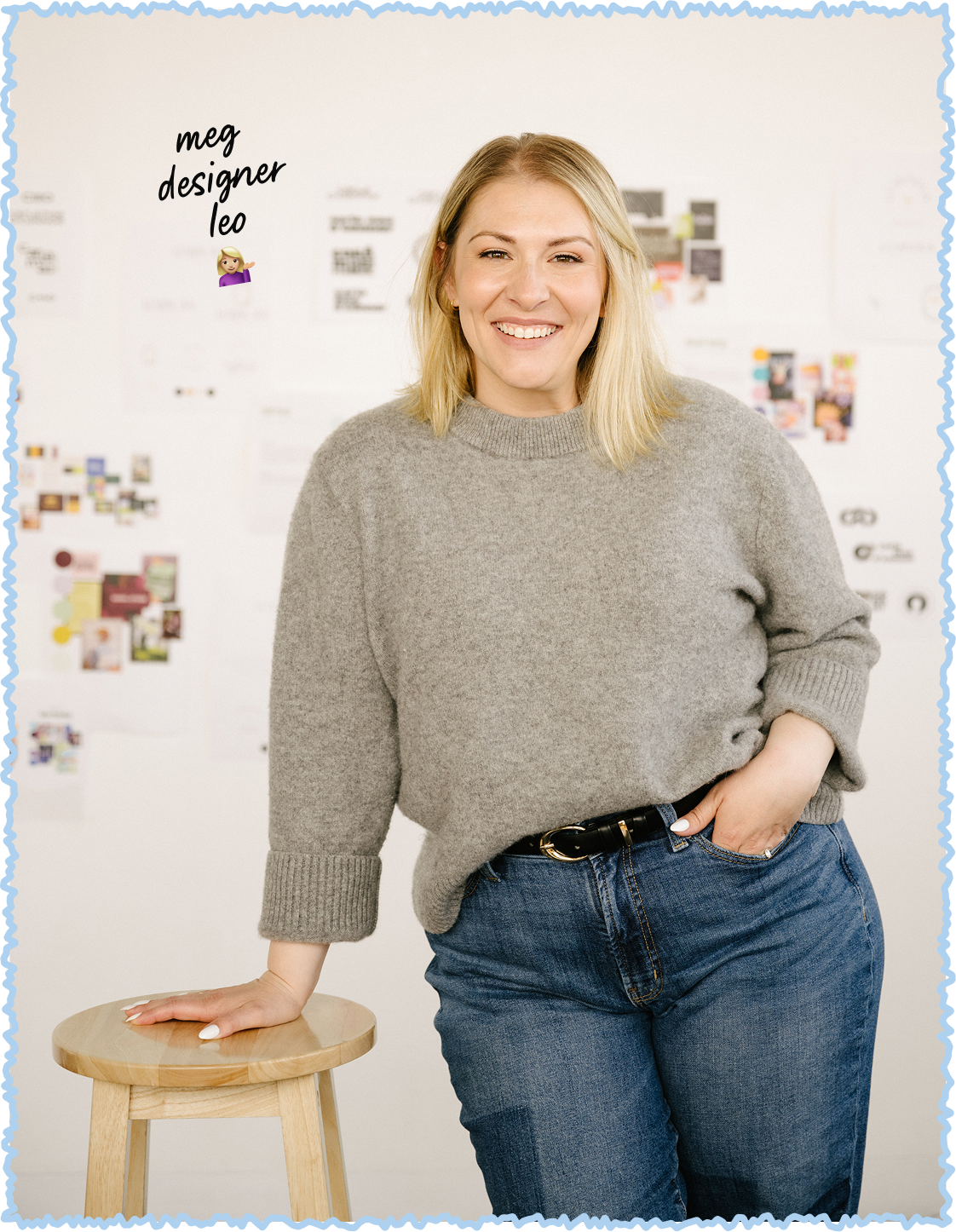 A woman with blonde hair, wearing a gray sweater and blue jeans, smiling and leaning with one hand on a wooden stool in a room with a white wall covered in colorful papers and notes. The text on the top left reads, "meg designer leo".