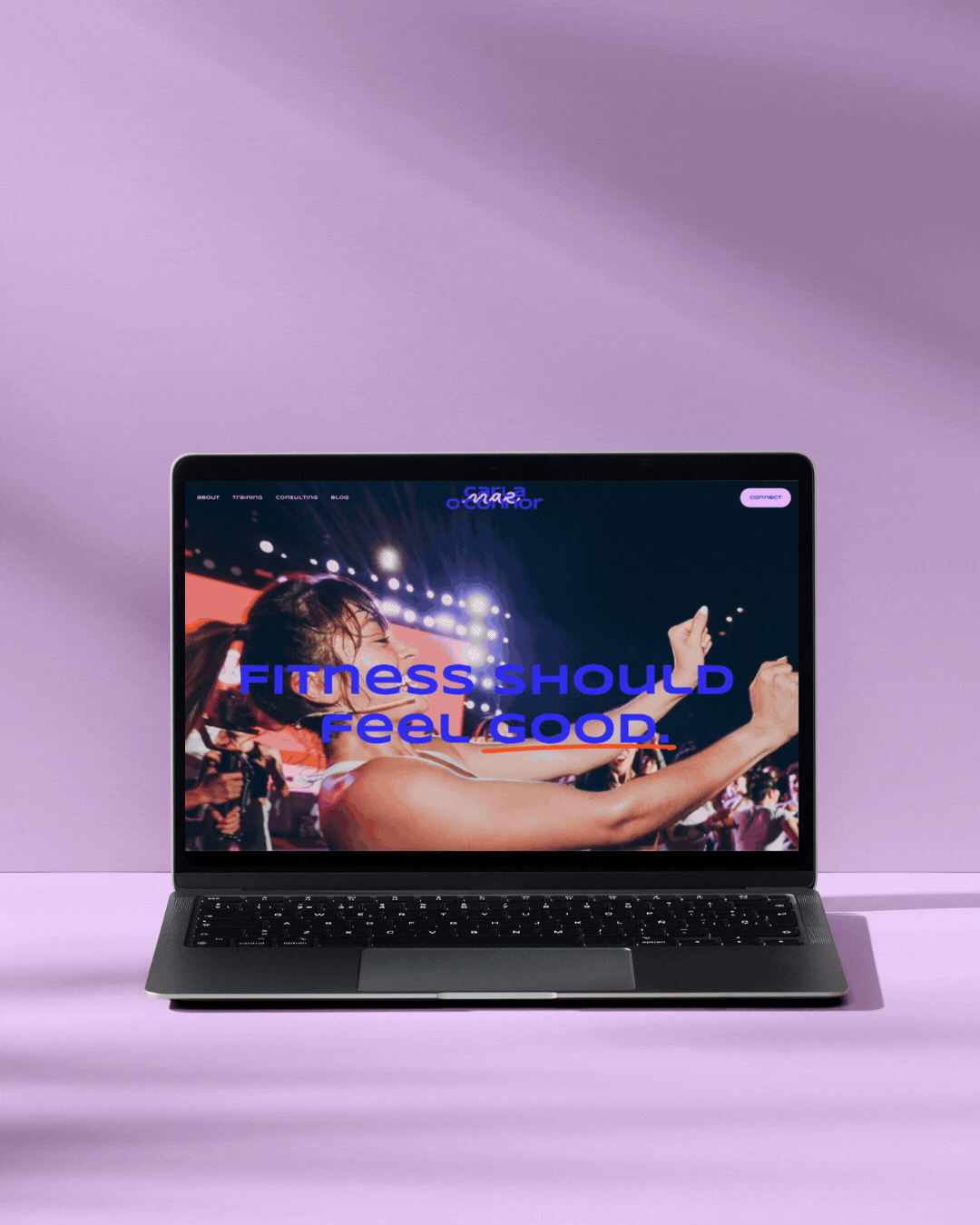 Laptop displaying a fitness website, Carla Mae O'Connor Consulting, with a woman exercising on stage, with the text "Fitness Should Feel Good" in blue and orange.