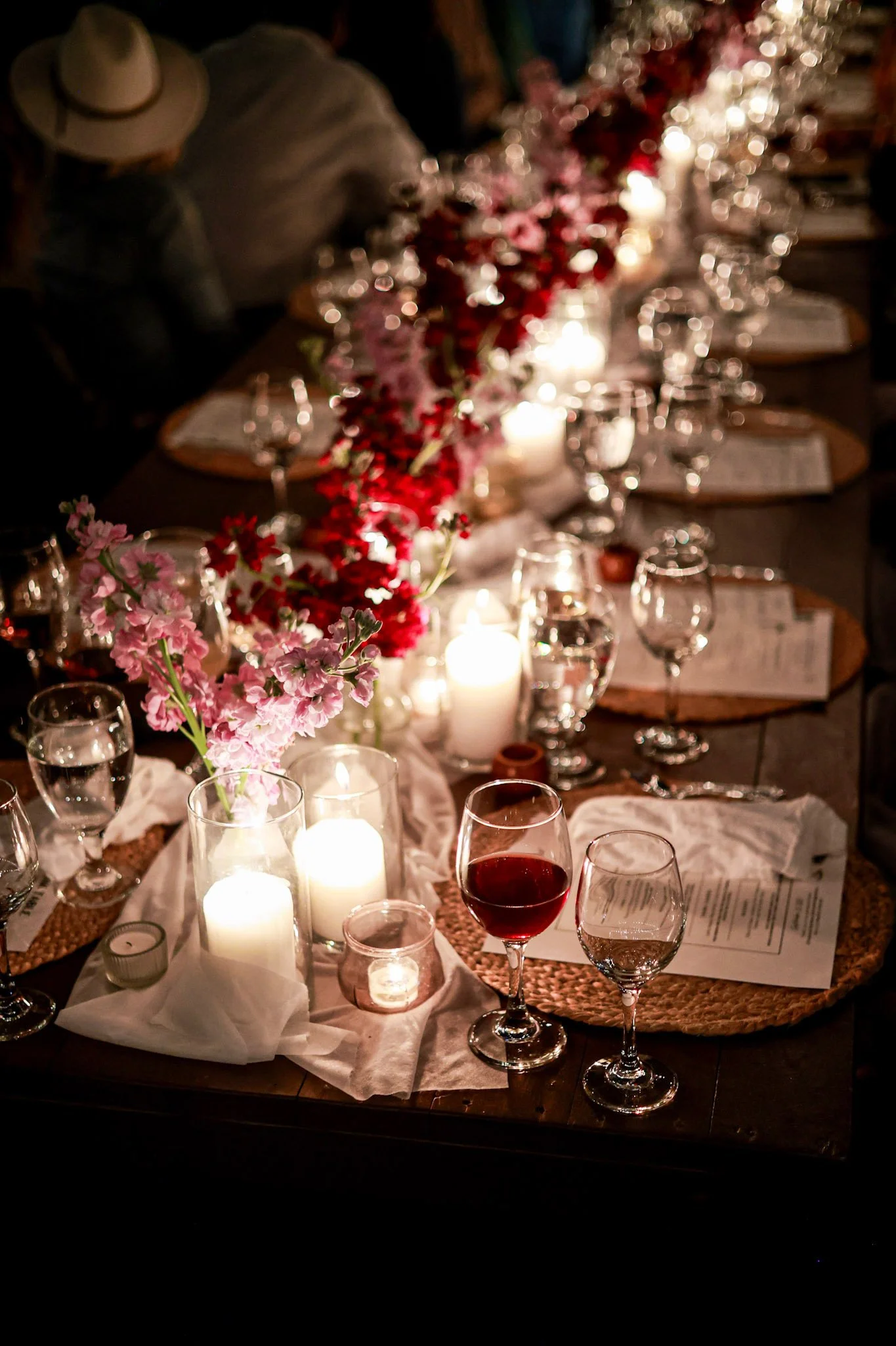 Candlelit private dining table with seasonal flowers, wine glasses, and elegant place settings at a Hearth & Harvest live-fire catered event in Southern California.