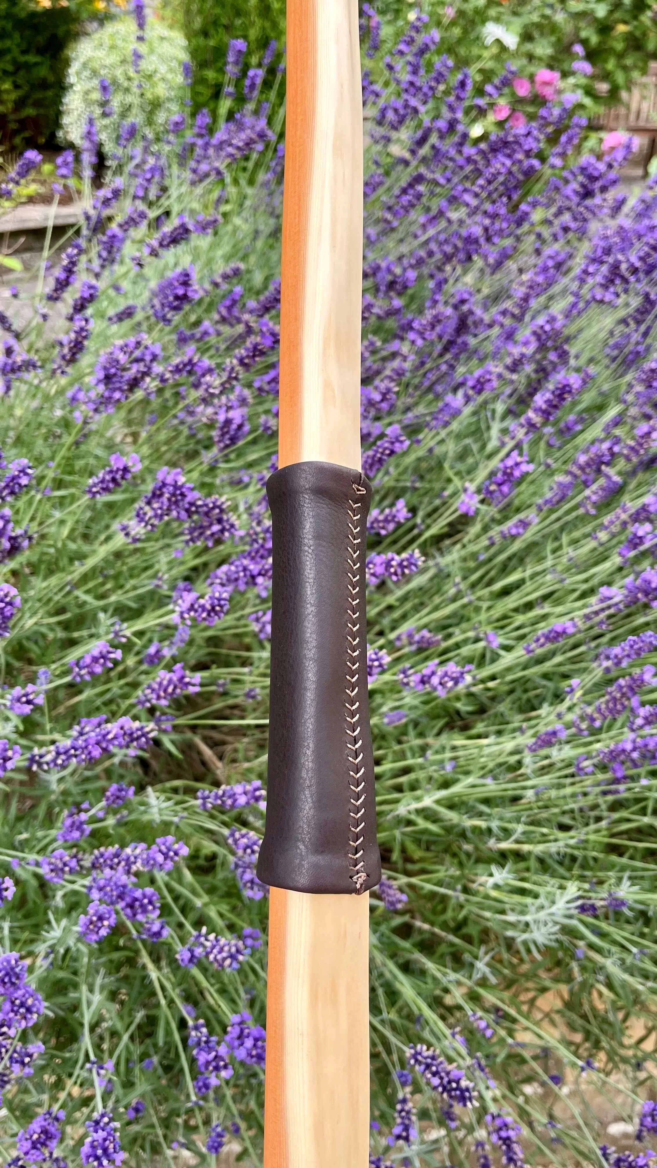 Close-up of a hand stitched, dark brown leather bow handle in relation to the burnt arrow pass.
