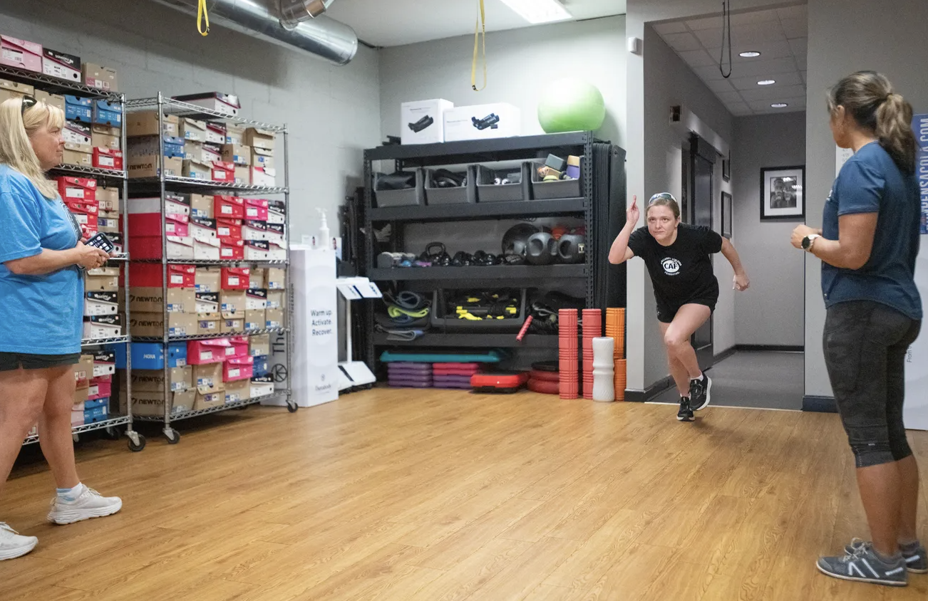 From left, Mia Erickson Stevens looks on as her daughter, a Paralympic hopeful, Kira Stevens, 19, runs during a physical therapy session for Dr. Lynne Virant, PT, DPT, at the Movement Clinic in the Running Wild building in Pensacola on Tuesday, July 