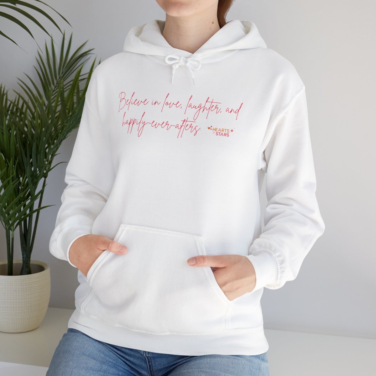 Person wearing a white hoodie with text 'Believe in love, laughter, and happy-ever-afters' in pink.