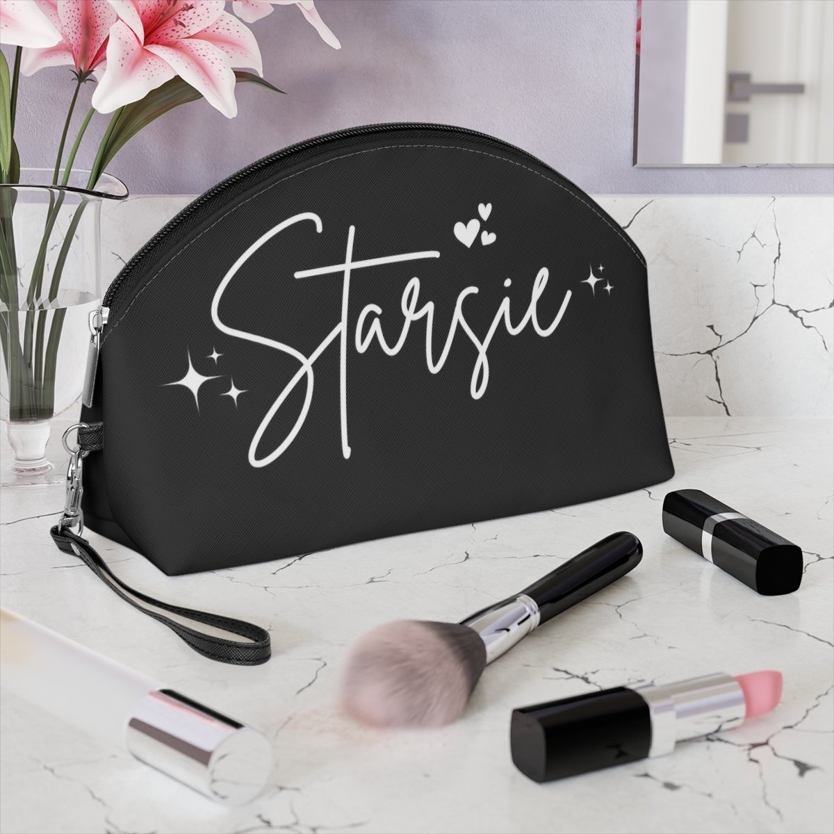 Makeup bag with "Starsie" inscription, surrounded by lipsticks, brushes, and a flower vase on a countertop.