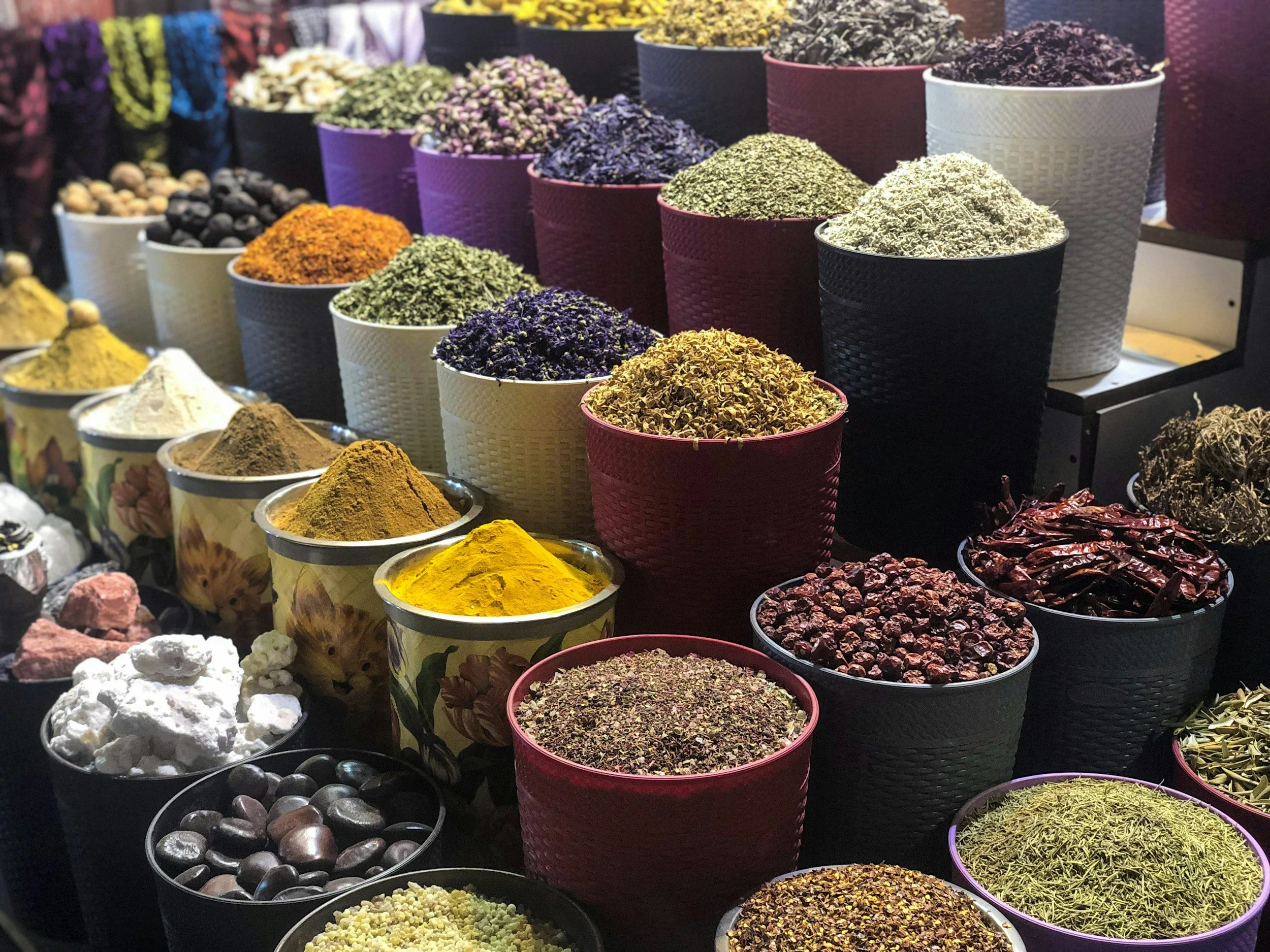 Market stall with colorful containers and bowls filled with various spices, herbs, and dried ingredients.