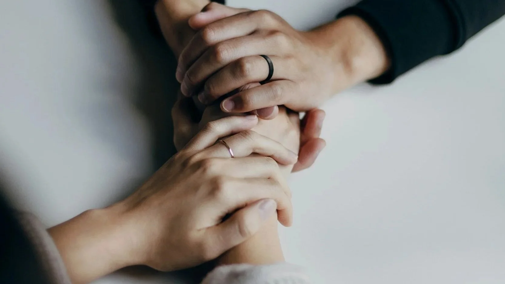 two people holding both of each others hands across a table in a comforting gesture