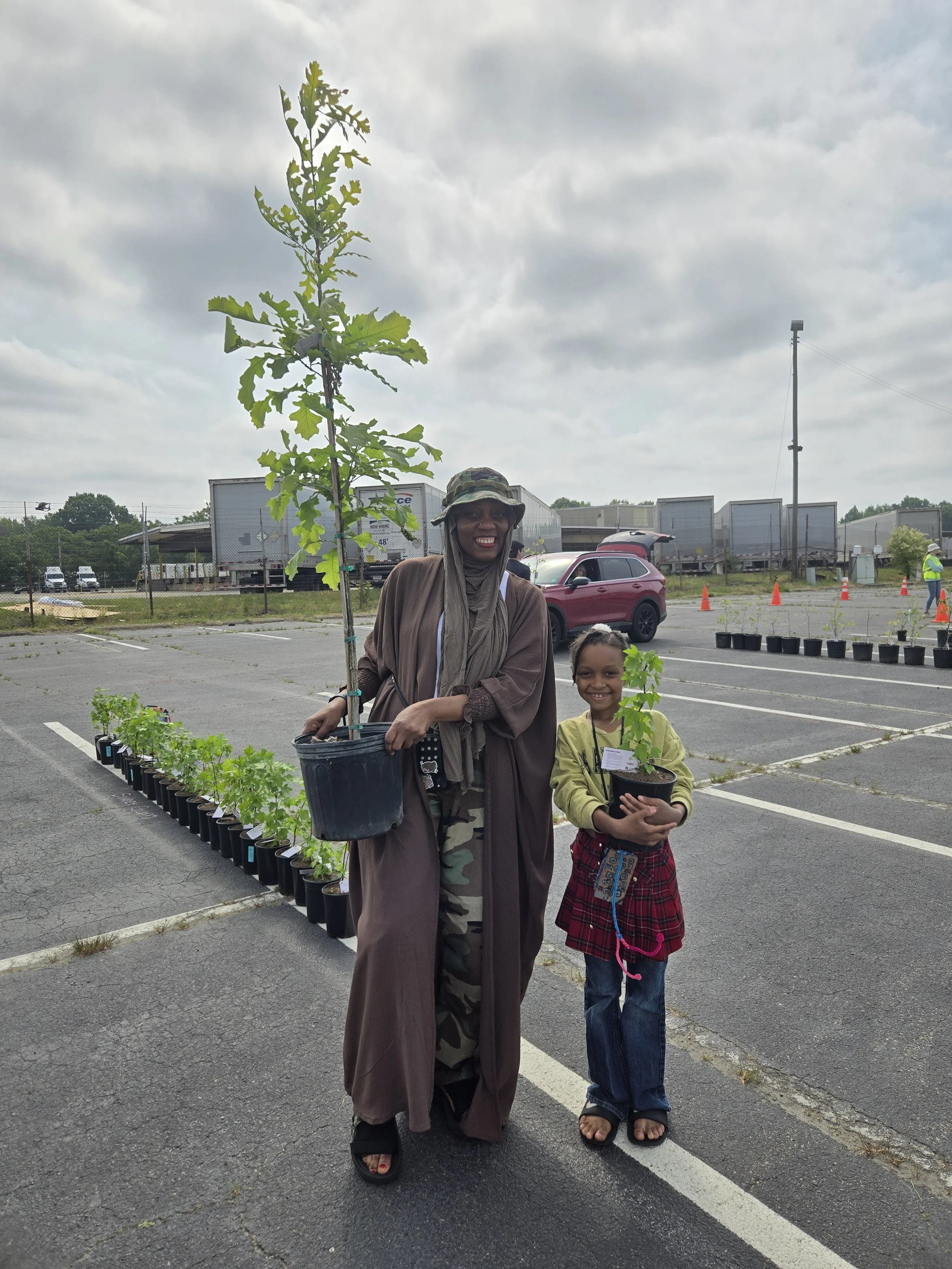 Photo of a community member and her daughter posing with the two trees they took home from the giveaway.