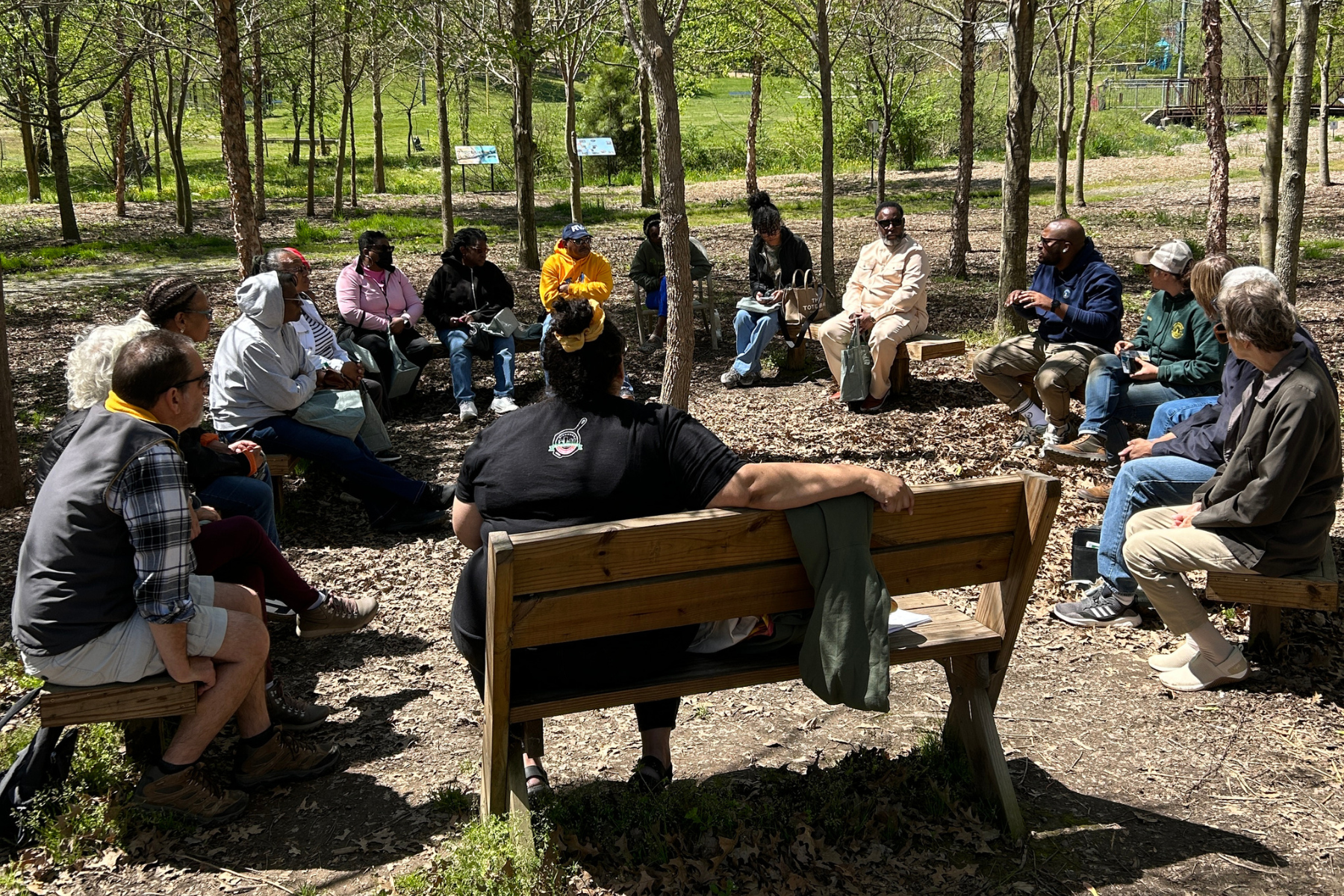 Community members gather under the canopy at Bellemeade's Outdoor Classroom for a discussion on community greening.