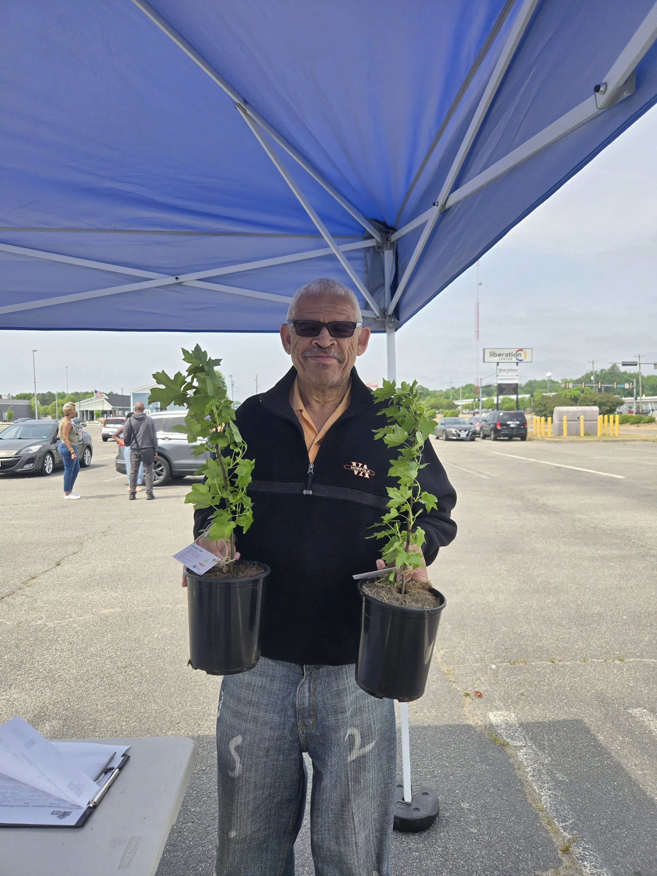 Photo of a community member posing with the two trees he took home from the giveaway.